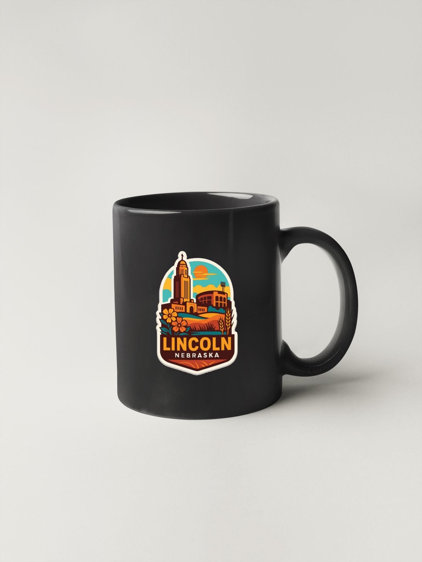 A black coffee mug with a colorful graphic depicting the Lincoln, Nebraska skyline.