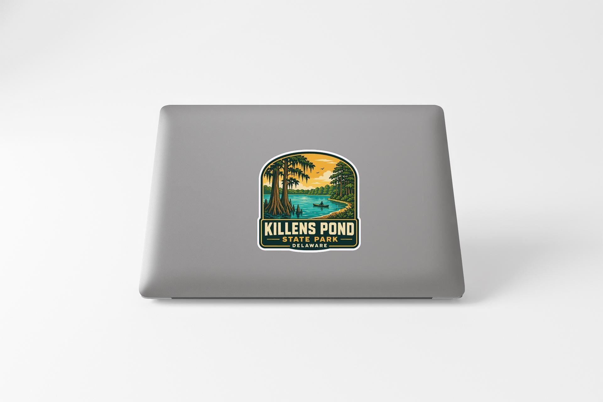 a sticker on a laptop that depicts a tropical landscape with palm trees, a lake, and a sunset.