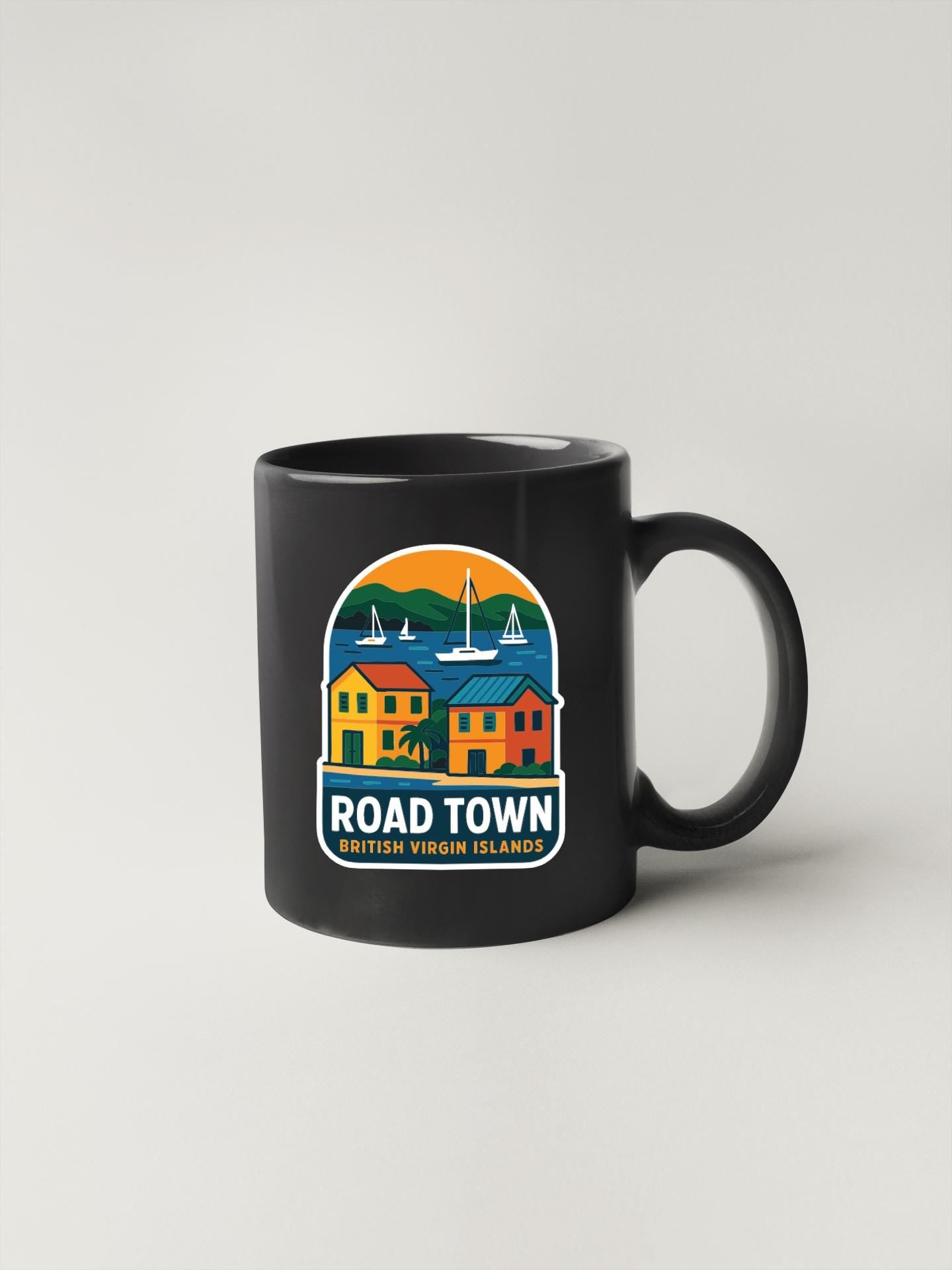A black coffee mug with a colorful graphic design depicting a coastal town scene with boats and buildings.