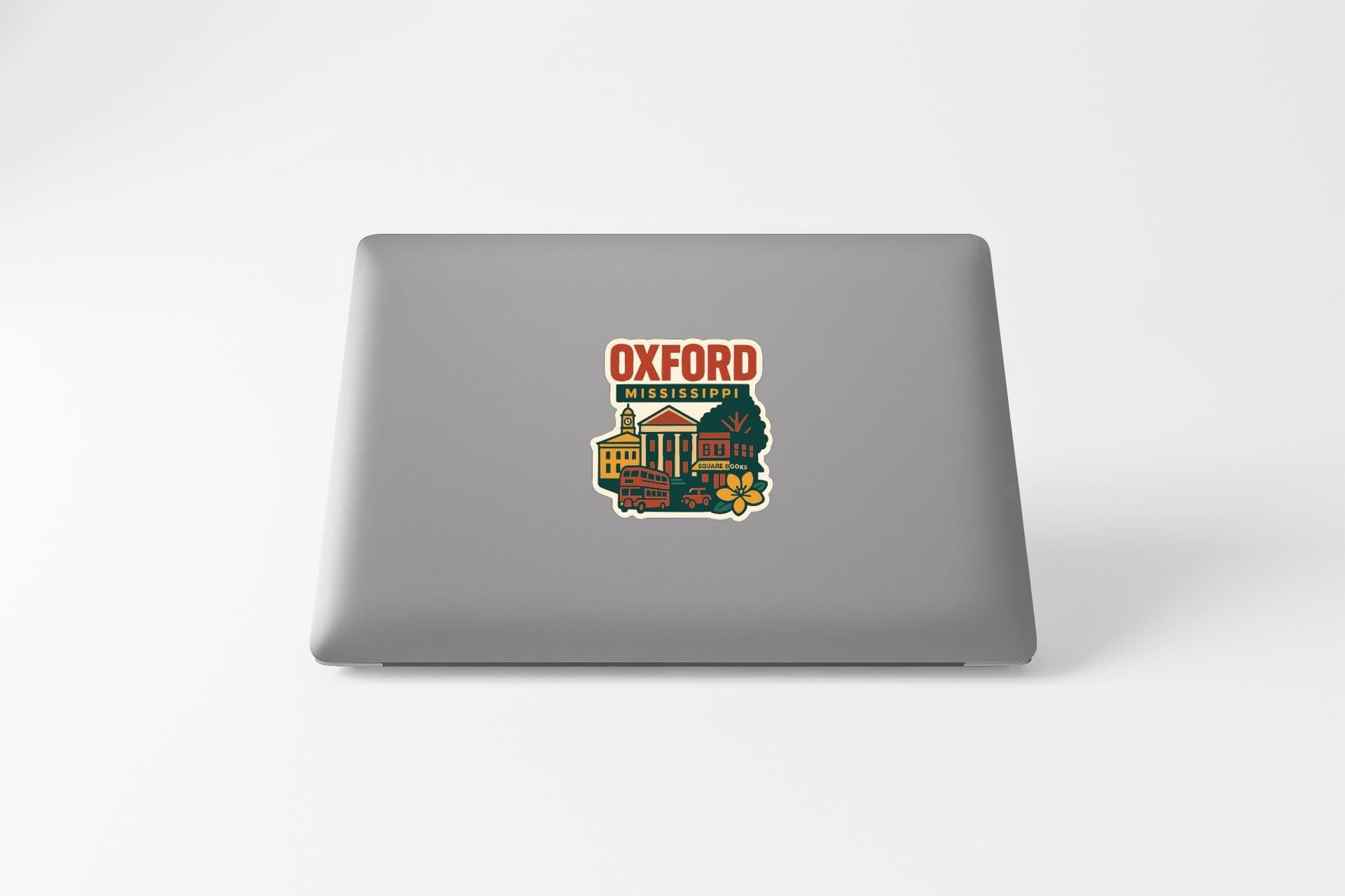 a sticker with a colorful illustration of a cityscape and the text "Oxford Mississippi" on the back of a laptop.