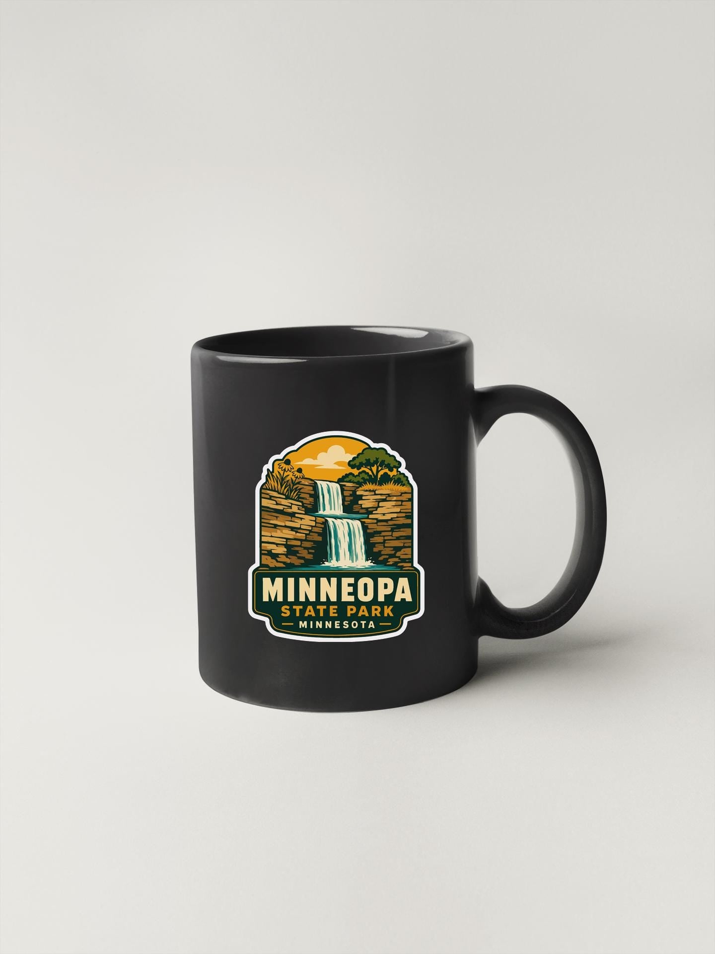 A black coffee mug with a graphic design depicting a waterfall and the text "MINNEOPARK, MINNESOTA" printed on it.