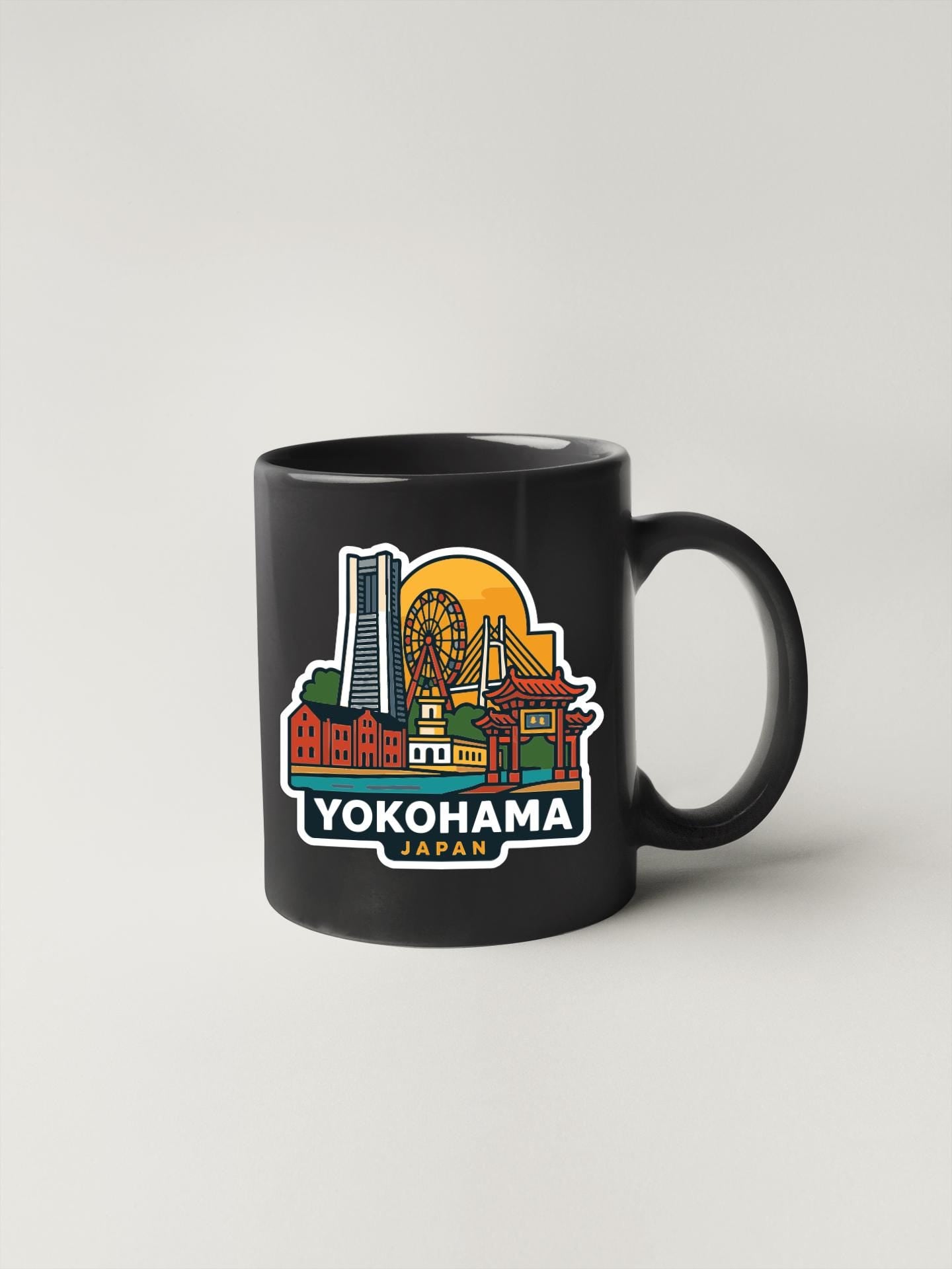 A black coffee mug with a colorful illustration of the city of Yokohama, Japan, featuring landmarks such as a ferris wheel, a temple, and a skyscraper.