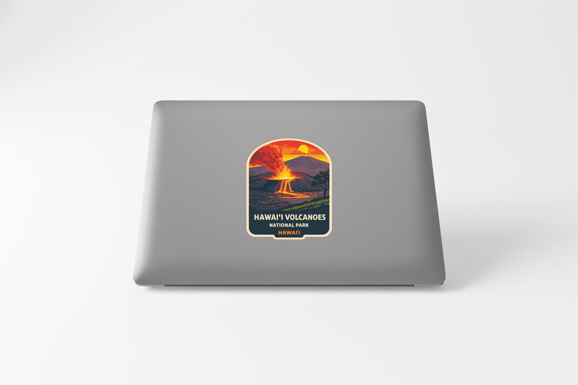 A sticker on the back of a laptop, depicting a Hawaiian volcano with a sunset in the background.