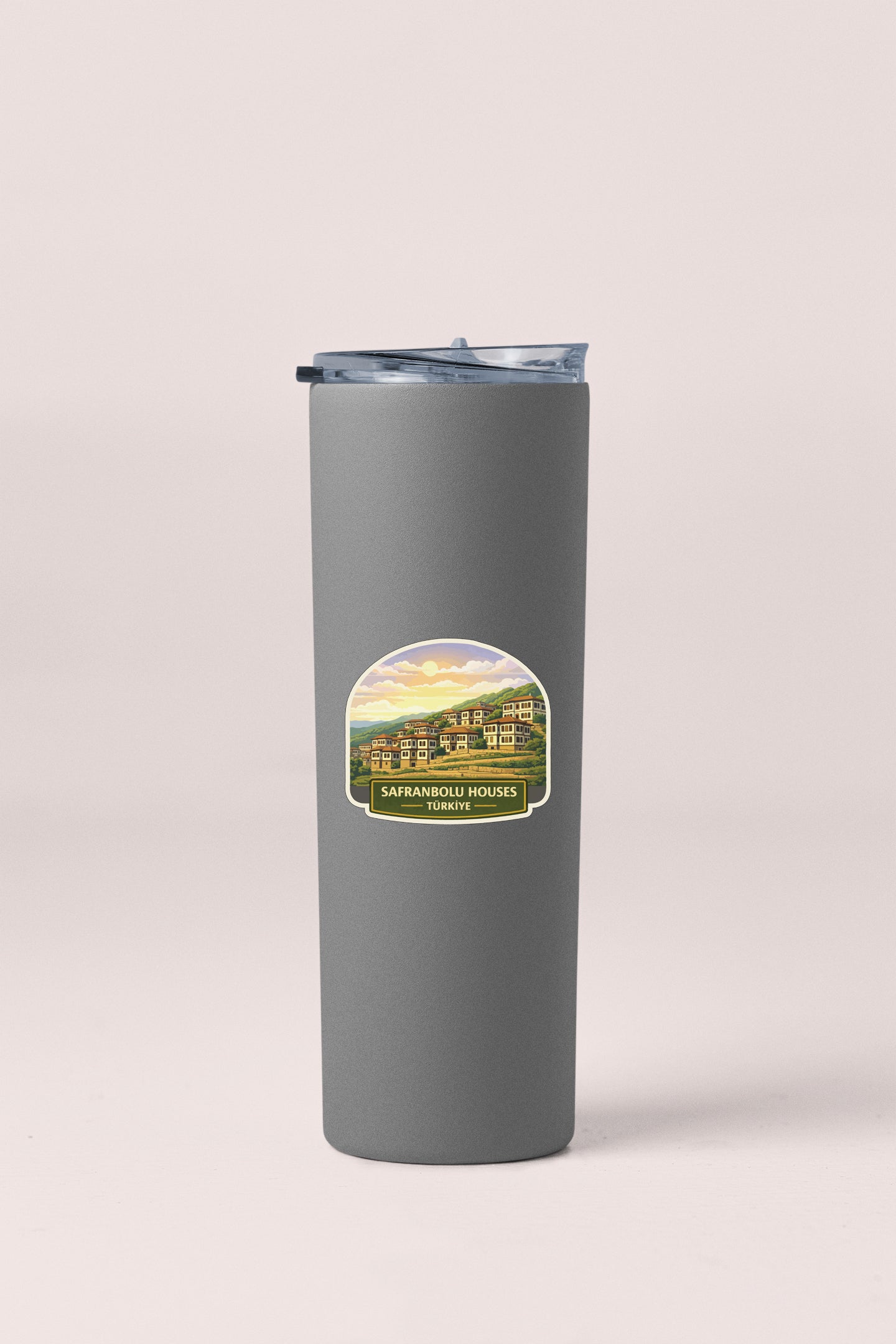 A gray insulated tumbler with a lid and a label featuring a scenic image of a house.