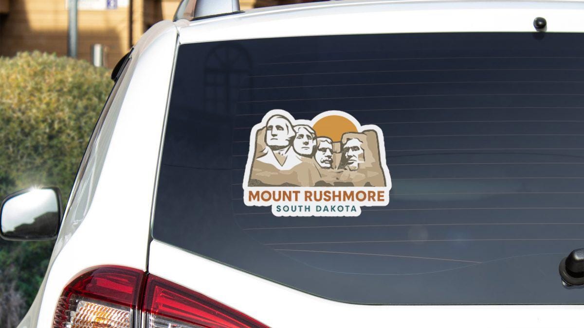 a sticker on the rear window of a vehicle that displays the faces of the four prominent mountains in South Dakota.