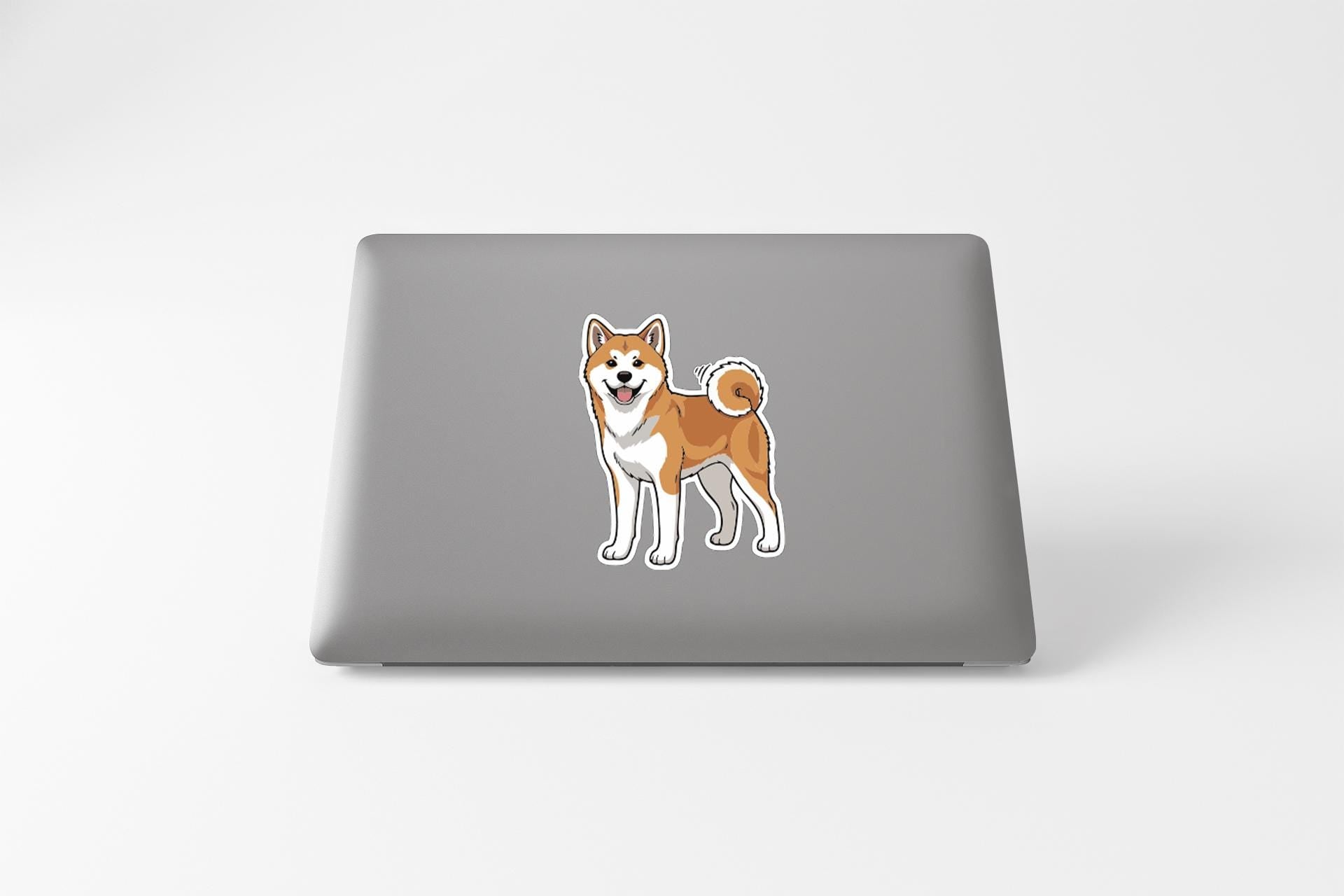 A sticker of a Shiba Inu dog is displayed on the back of a laptop computer.