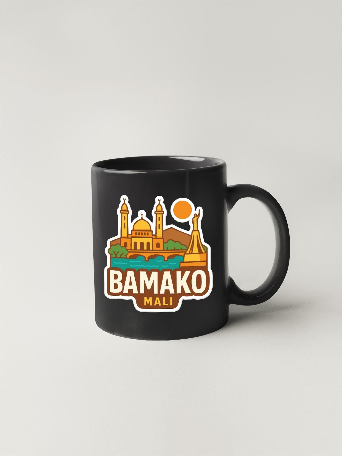 A black coffee mug with a colorful graphic design depicting the city of BAMAKO, Mali.