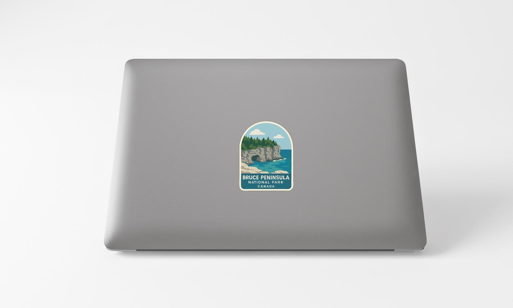 A sticker on the back of a laptop, depicting a scenic landscape with a cliff and a body of water.
