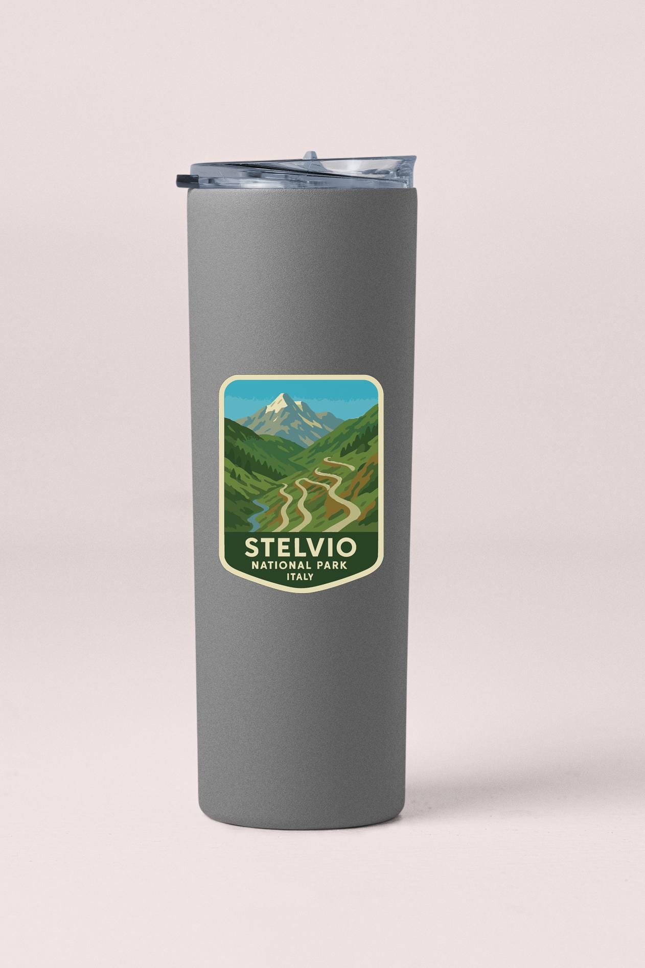 A gray insulated tumbler with a sticker depicting a scenic mountain landscape.