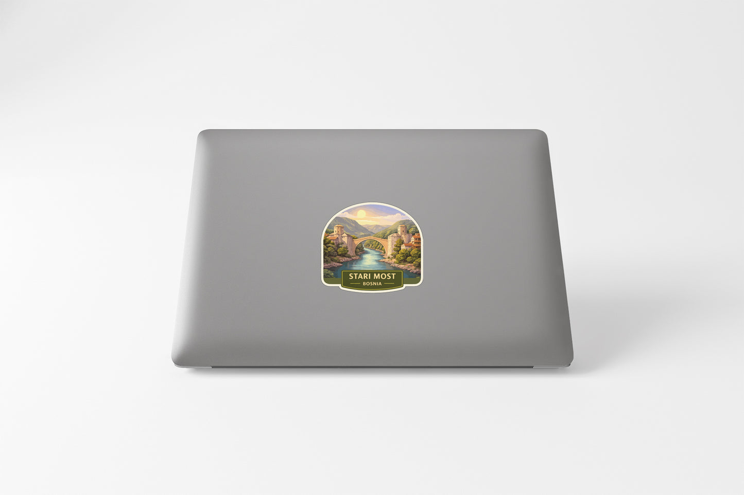 a sticker on the back of a laptop, depicting a scenic landscape with mountains and a river.