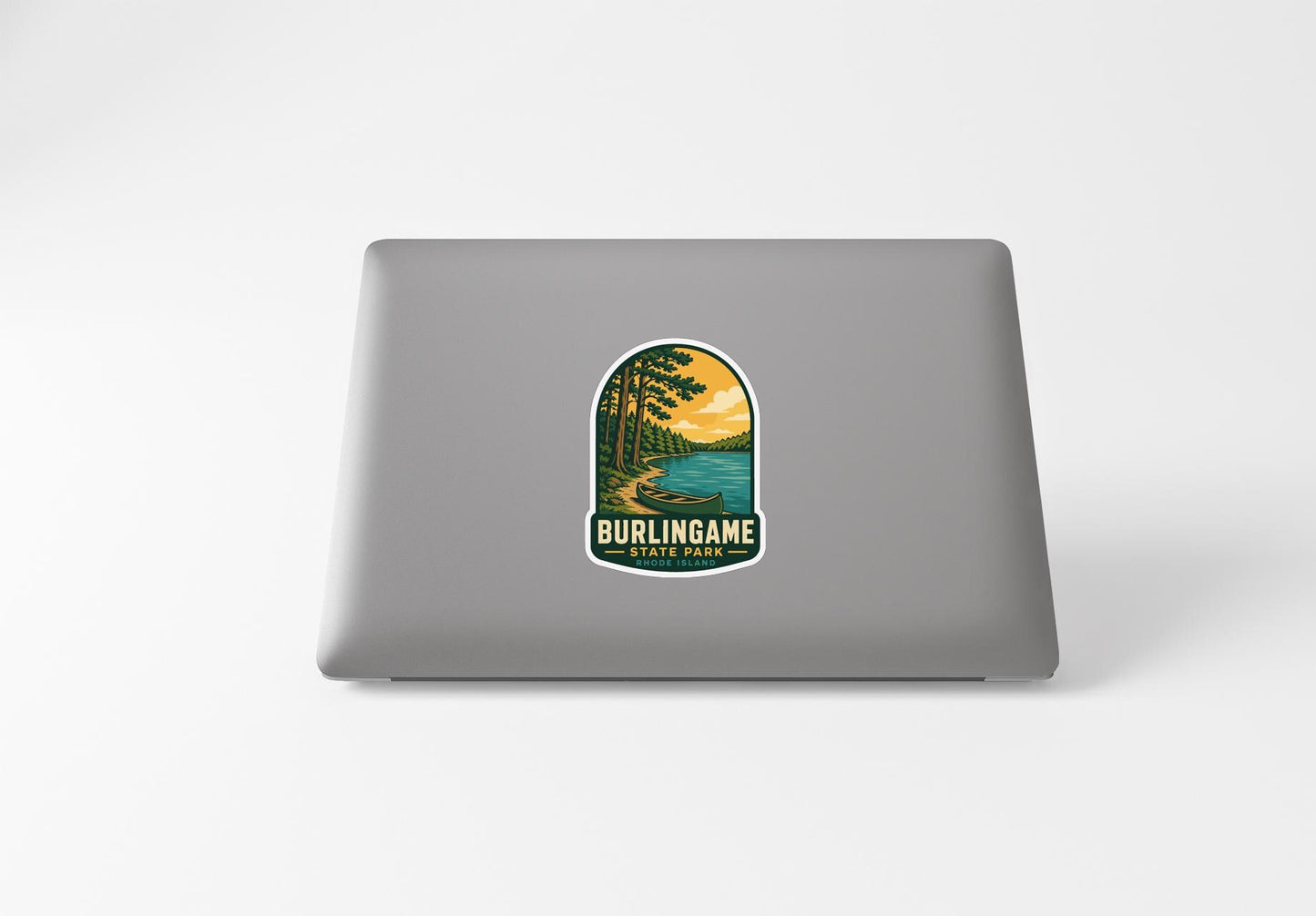 A sticker on the back of a laptop that features a scenic landscape with a lake, trees, and a sunset.