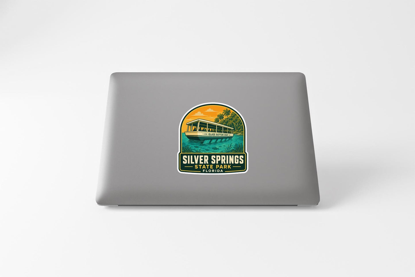 A sticker on the back of a laptop, depicting a boat on a lake with a scenic background.