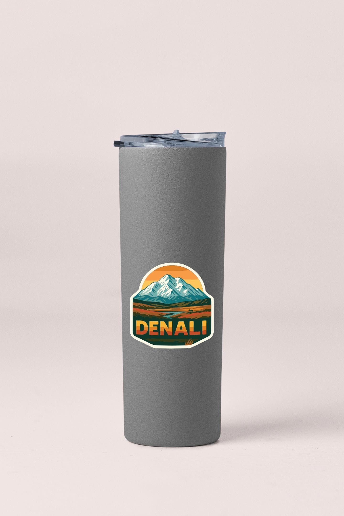 A gray insulated tumbler with a mountain landscape sticker on it.