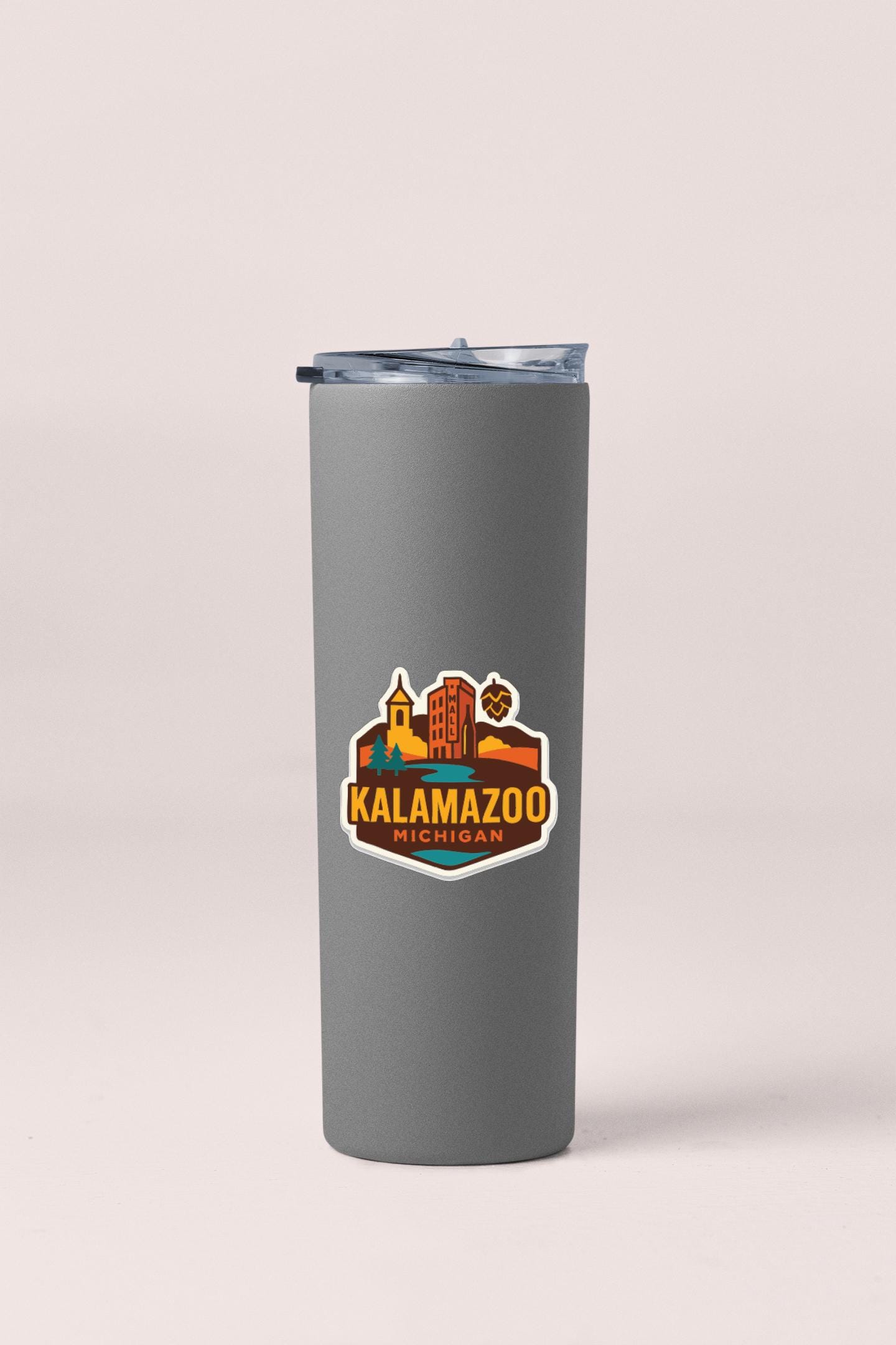 A gray insulated tumbler with a lid and a sticker featuring the text "KALAMAZOO, MICHIGAN" and an illustration of a city skyline.