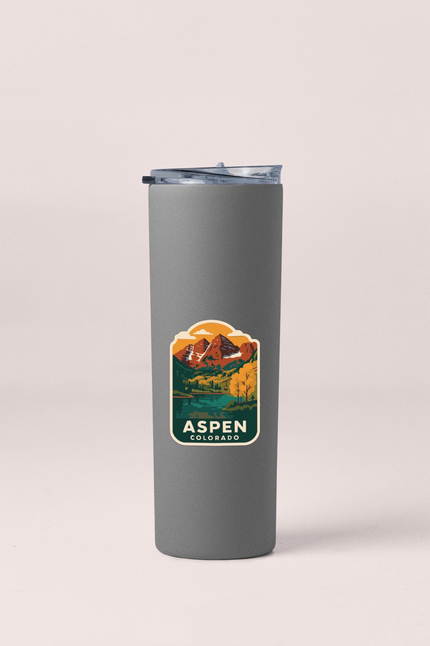 A gray insulated tumbler with a mountain landscape sticker on it, featuring the text "Aspen, Colorado".