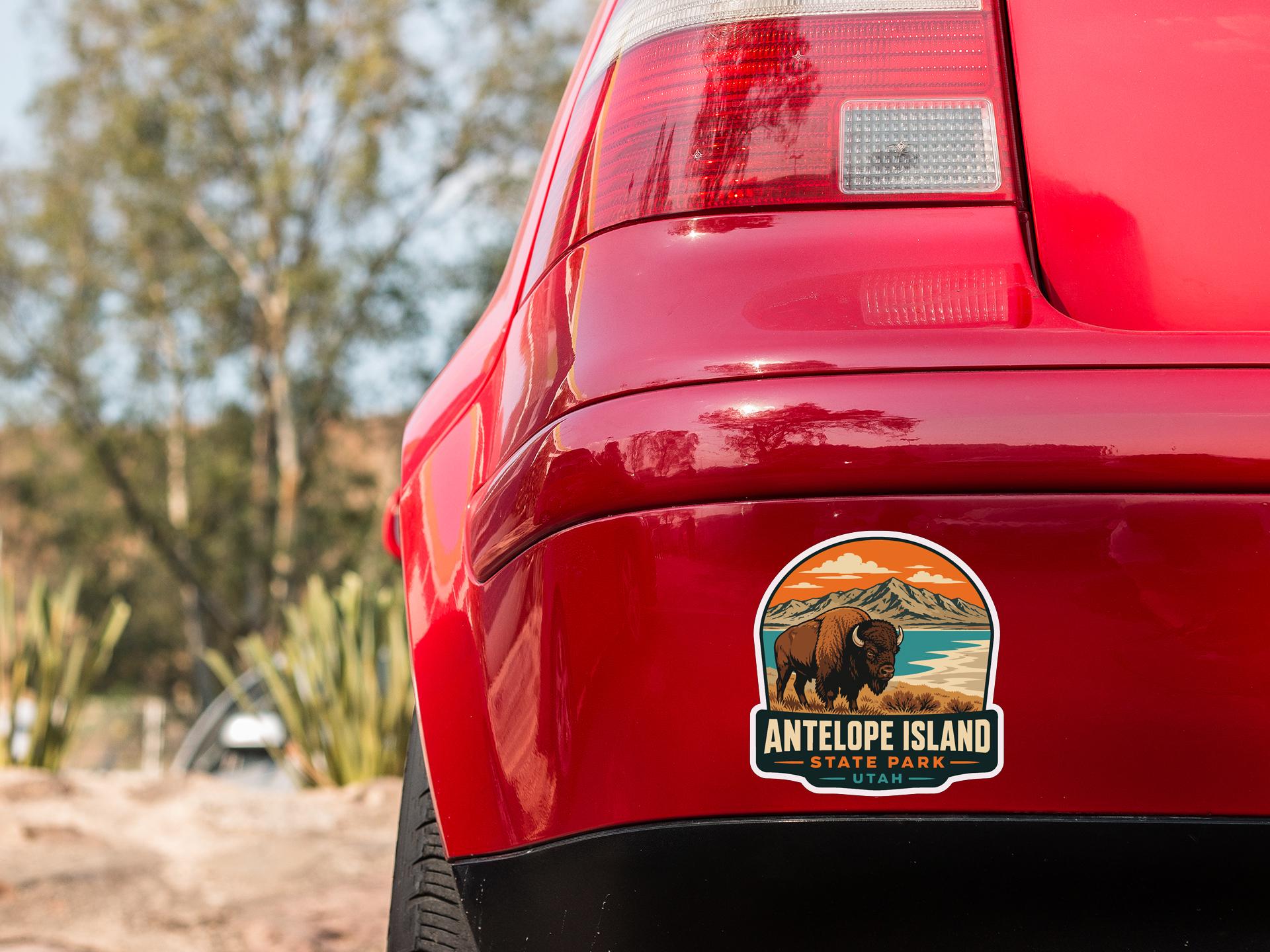 the rear end of a red car with a sticker on the trunk that says "ANTELOPE ISLAND STATE PARK UTA".