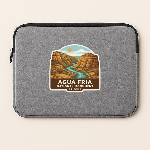 A gray laptop sleeve with a sticker depicting the scenic landscape of the Agua Frija National Monument in Arizona.