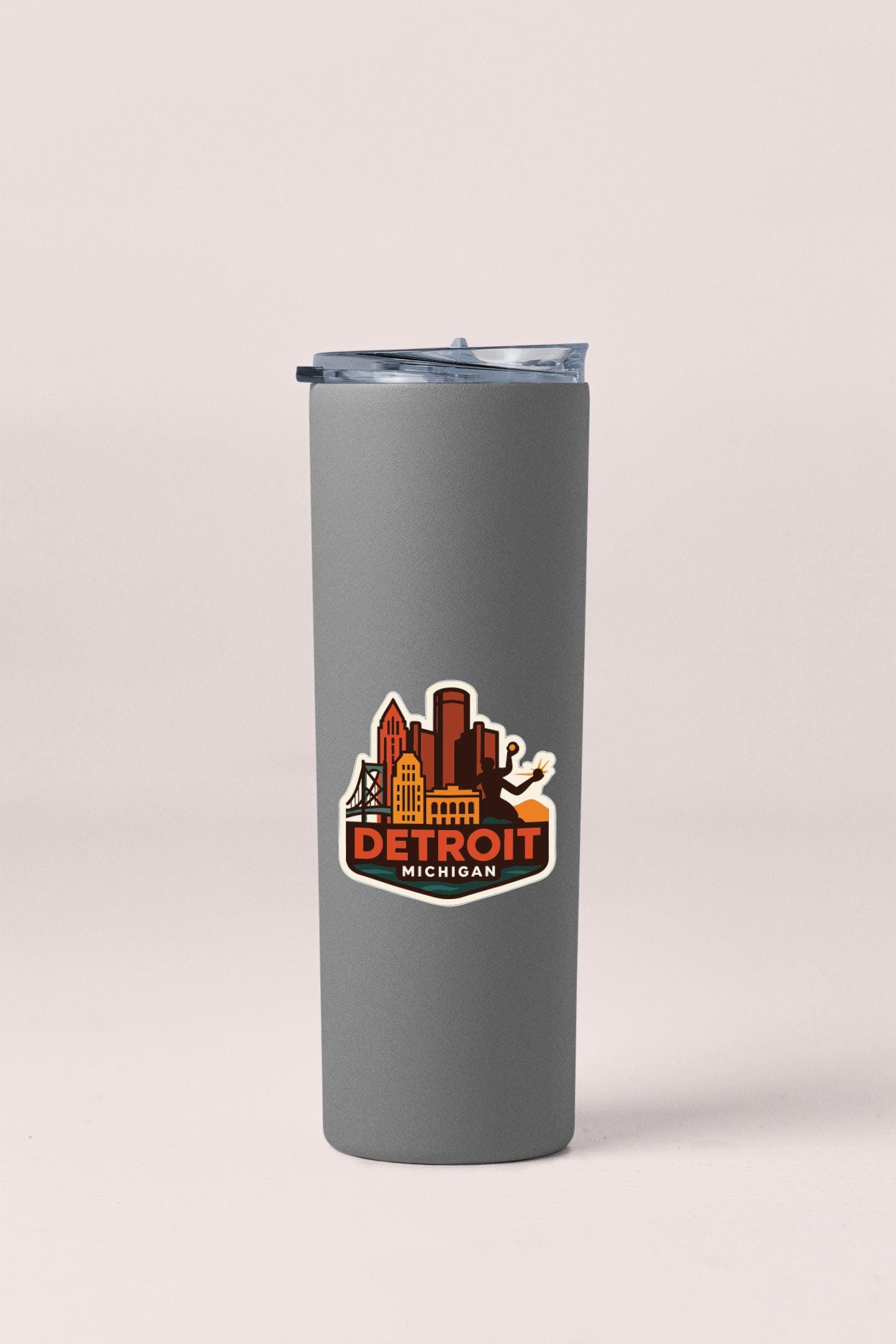 A gray insulated tumbler with a lid and a sticker featuring the city of Detroit, Michigan.