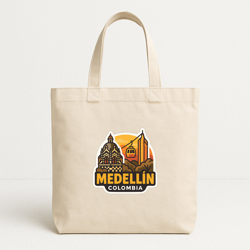 A beige tote bag with a printed design featuring the city of Medellín, Colombia, including a cable car and a building.