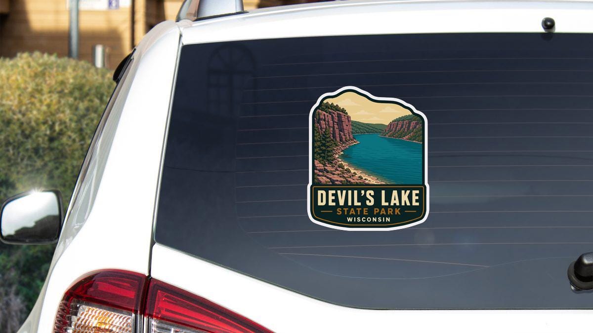 A sticker on the rear window of a white vehicle, depicting Devil's Lake State Park in Wisconsin.