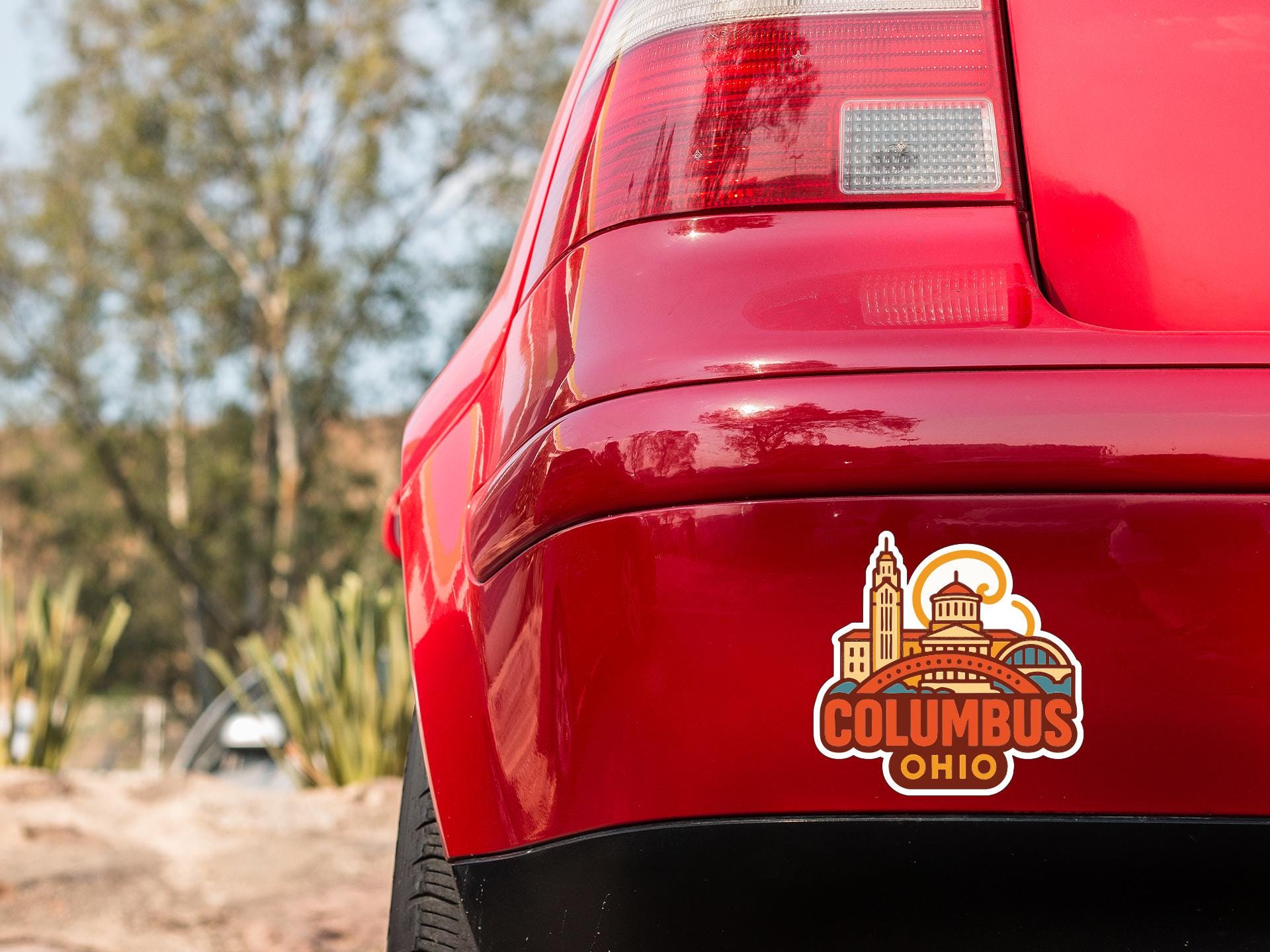 the rear end of a red car with a sticker on the trunk that says "Columbus Ohio".