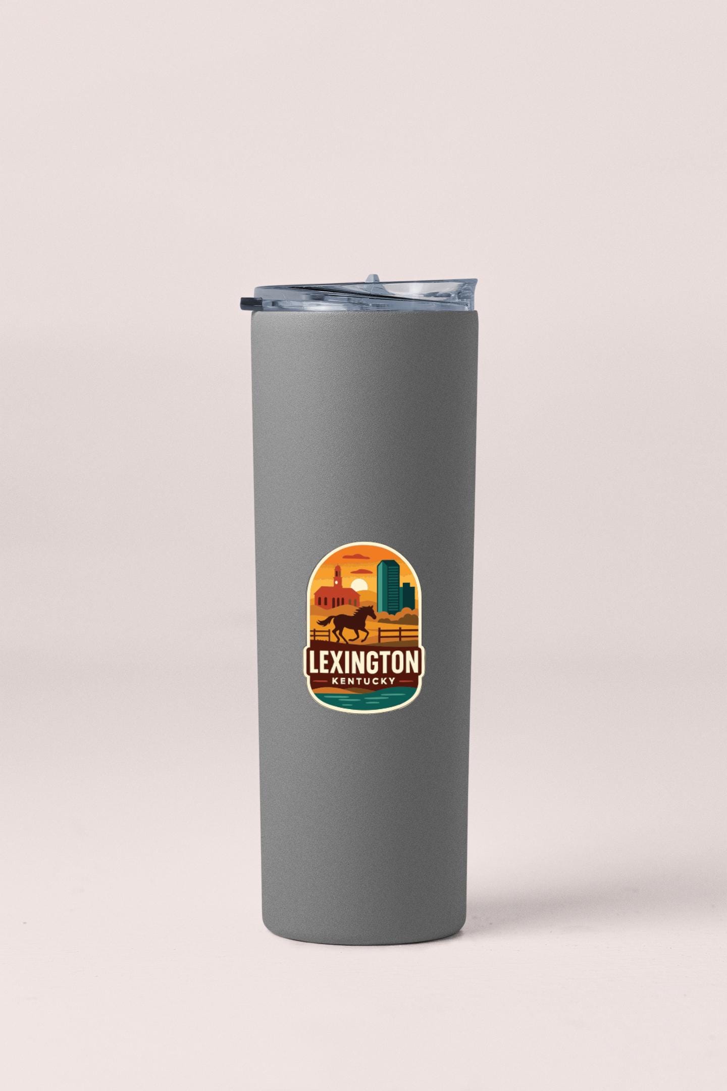 A gray insulated tumbler with a lid and a sticker featuring an illustration of a cityscape and a horse.