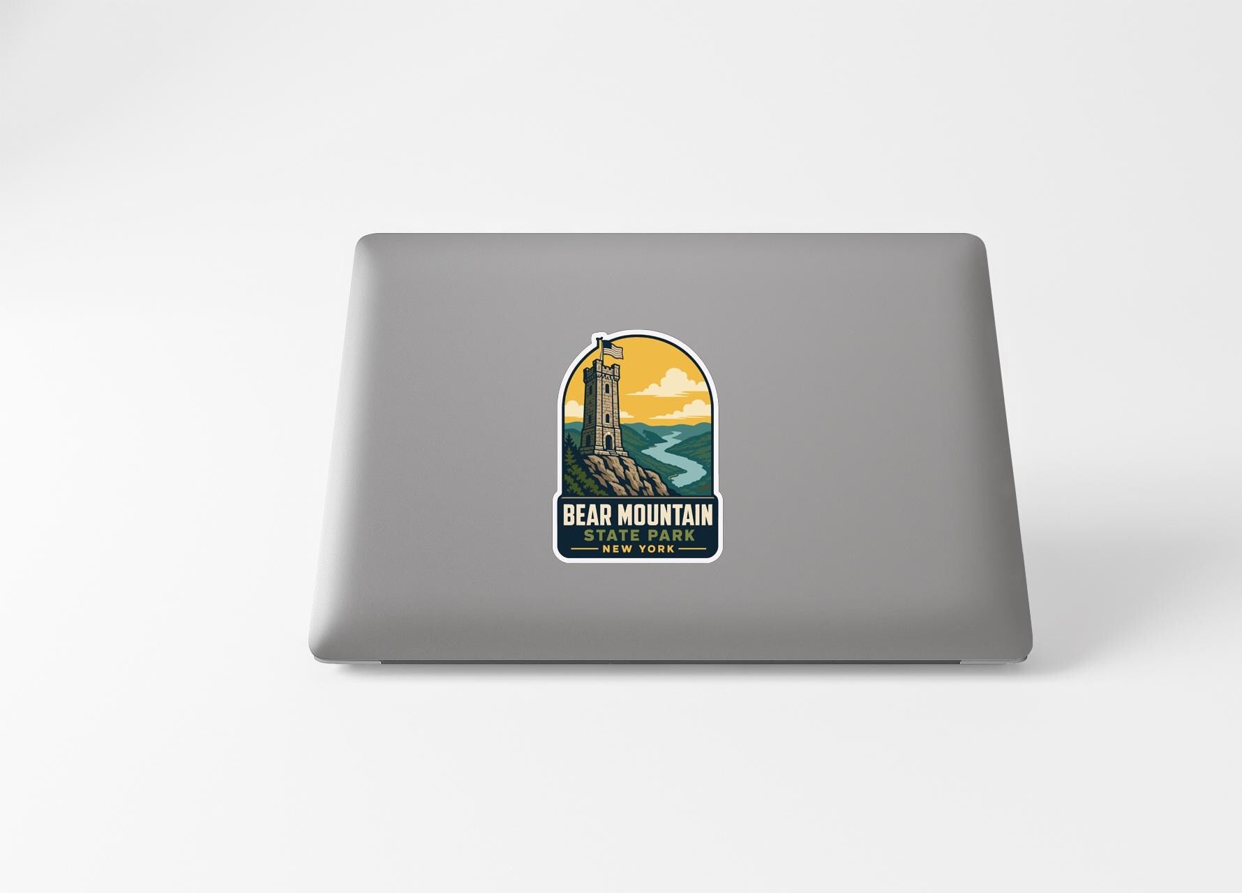 a sticker on a laptop that depicts a lighthouse on a cliff overlooking a body of water, with the text "BEAR MOUNTAIN STATE PARK NEW YORK" printed on it.