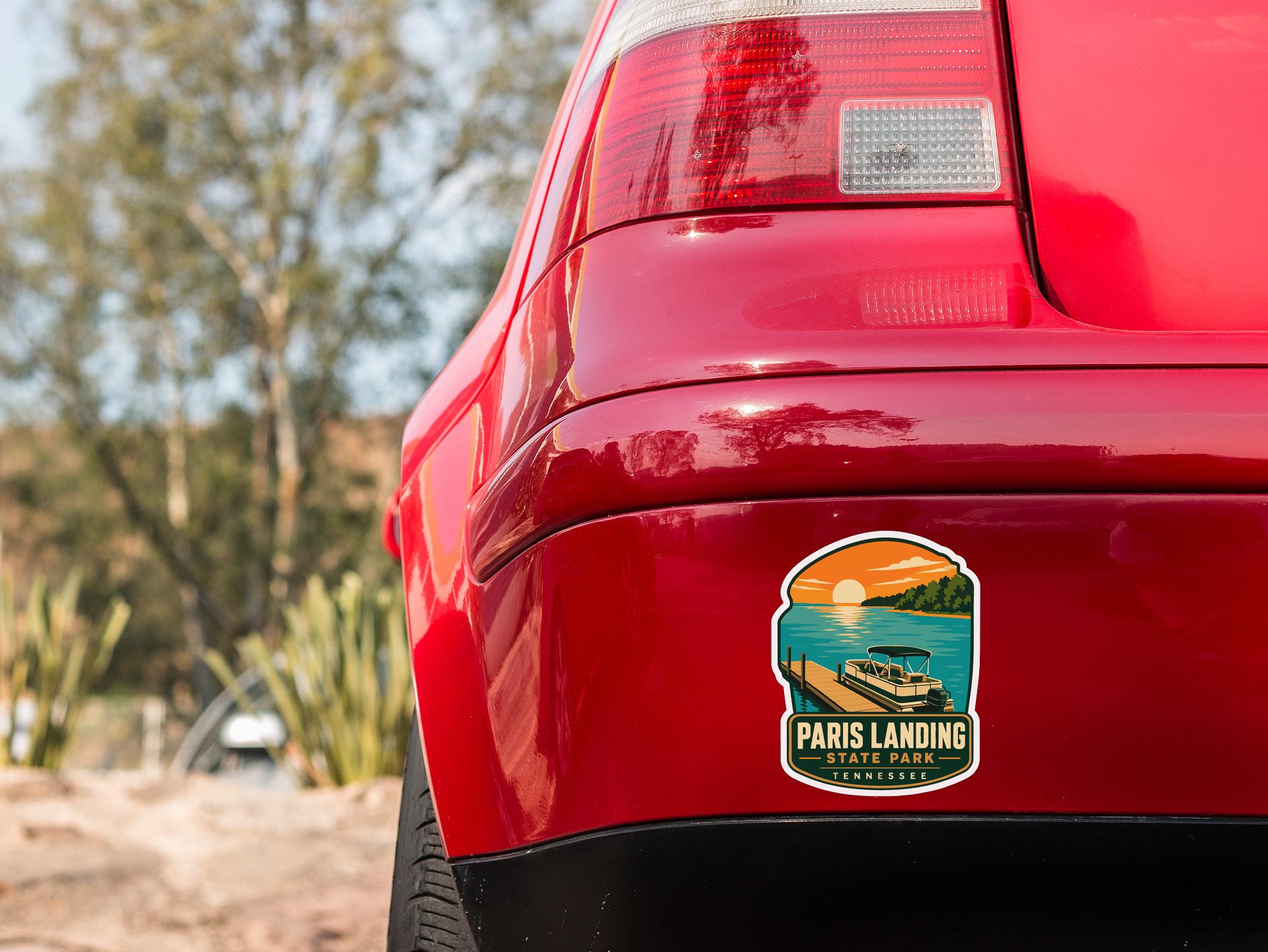 the rear end of a red car with a sticker on the back window that says "Paris Landing State Park, Tennessee".