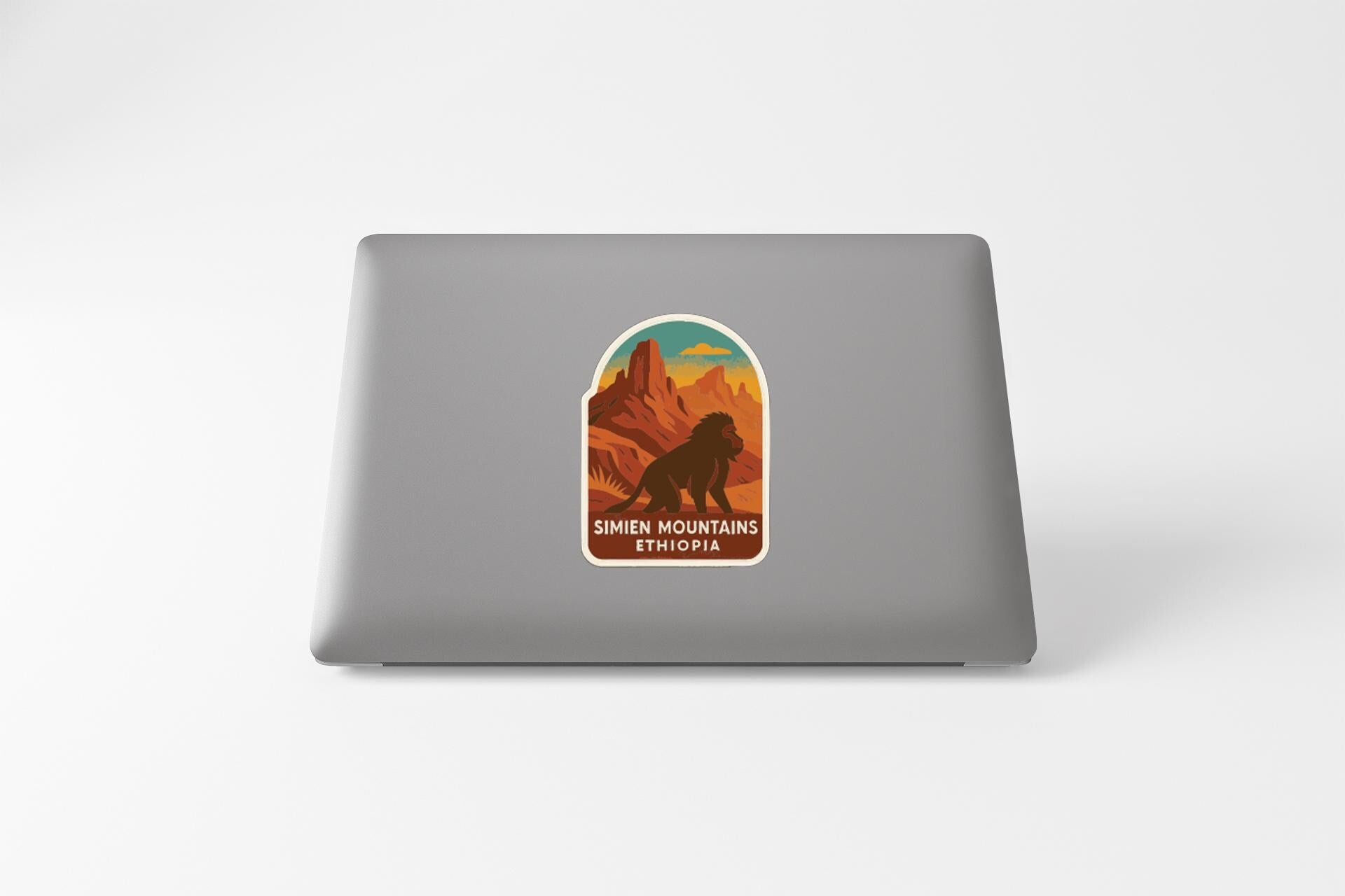 a sticker on the back of a laptop with a mountain landscape and a lion.