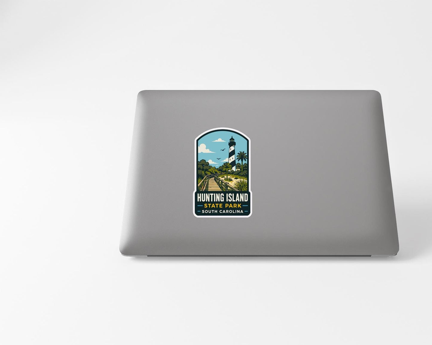 A sticker on the back of a laptop, depicting a lighthouse and a scenic landscape.