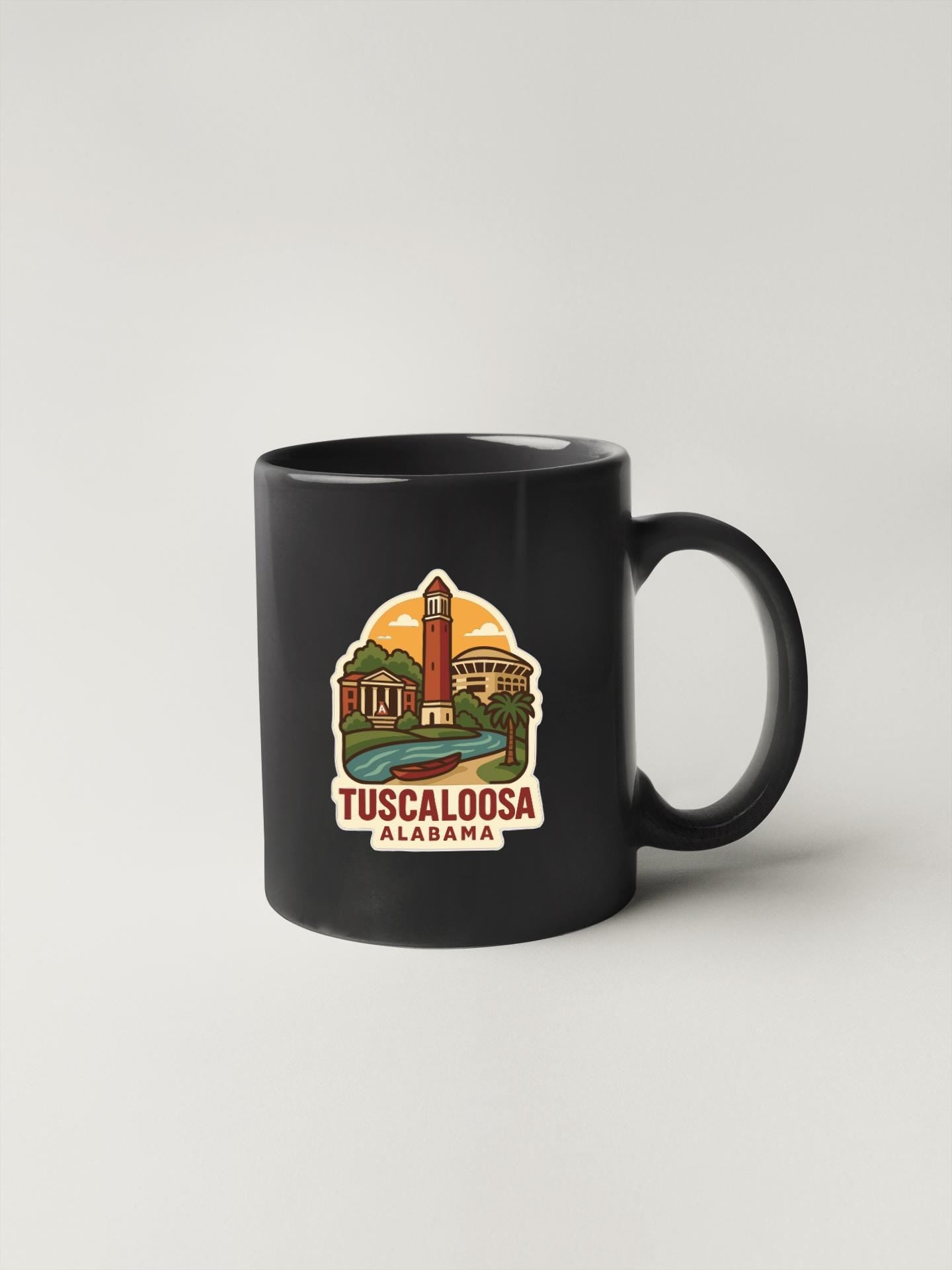 A black coffee mug with a colorful illustration of a landmark in Alabama and the text "TUSCALOOSA ALABAMA" printed on it.