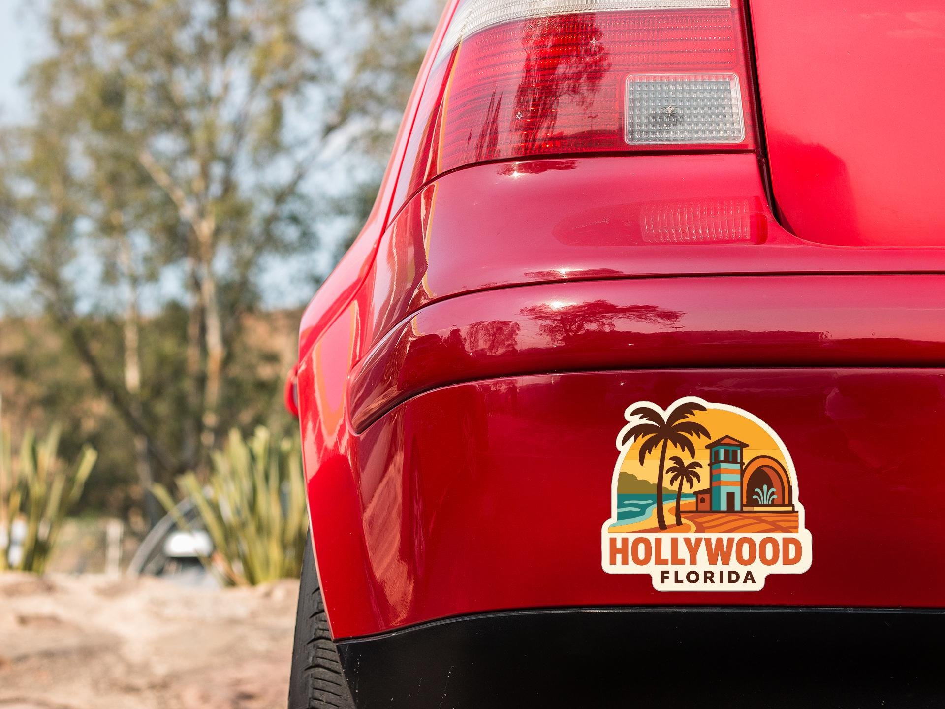 the rear end of a red car with a sticker on the trunk that says "Hollywood Florida".