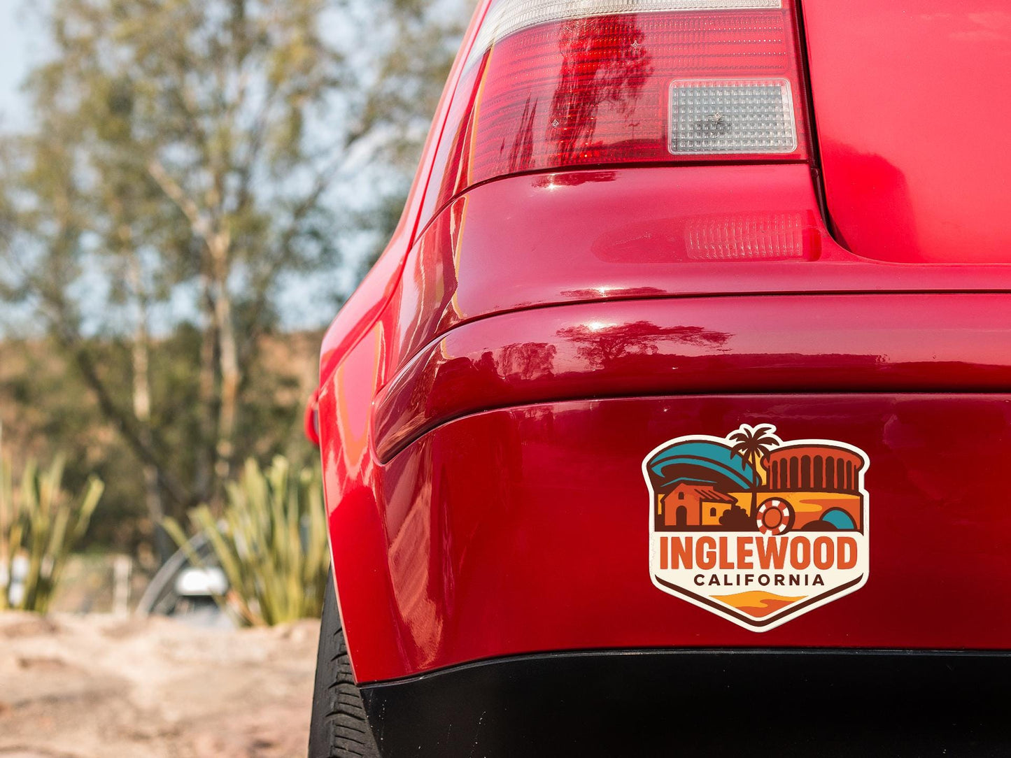 the rear end of a red car with a sticker on the trunk that says "INGLEWOOD CALIFORNIA".