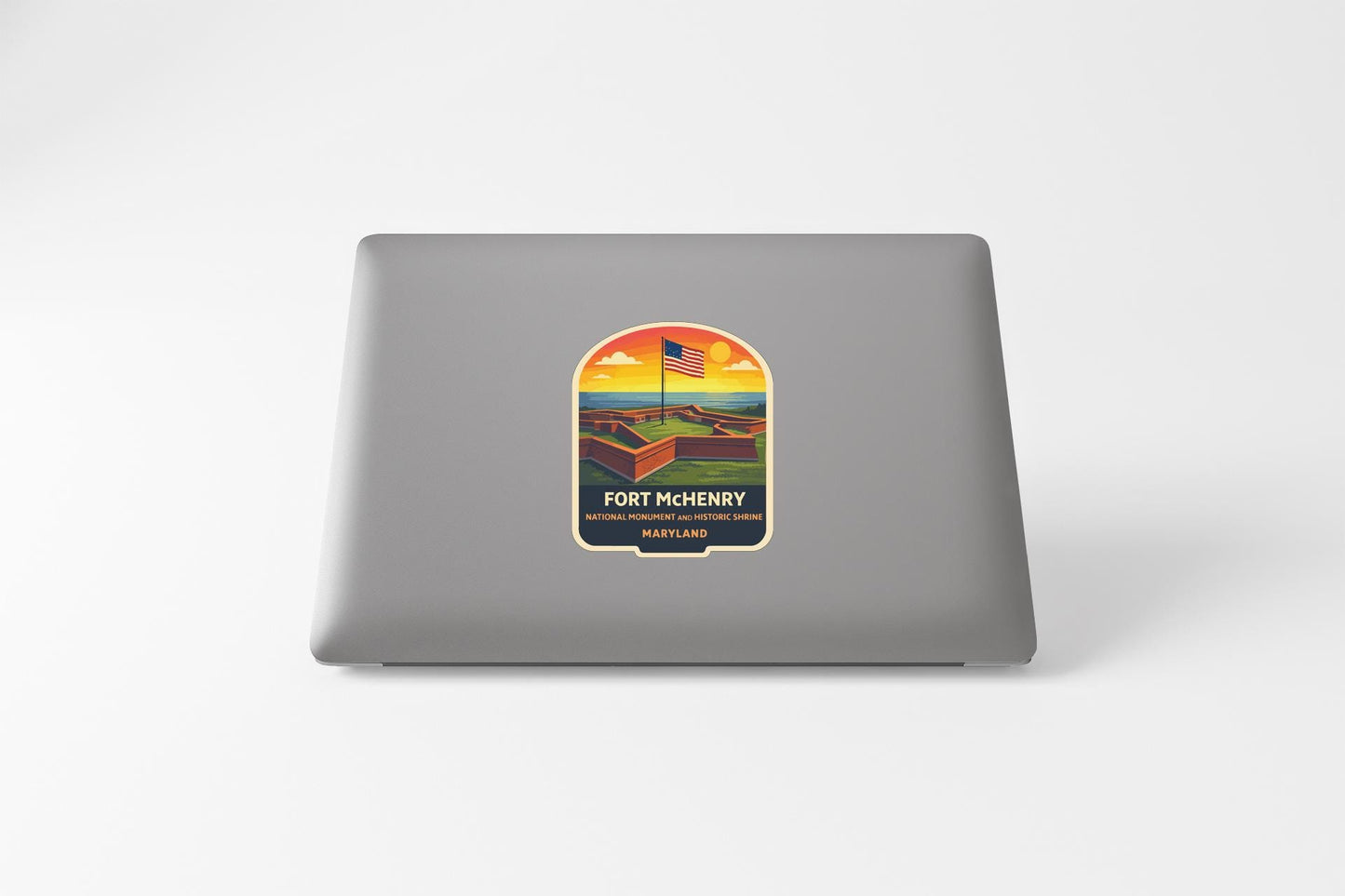 A sticker on the back of a laptop, depicting a scenic landscape with a flag and the text "Fort Mchenry National Historical Park"