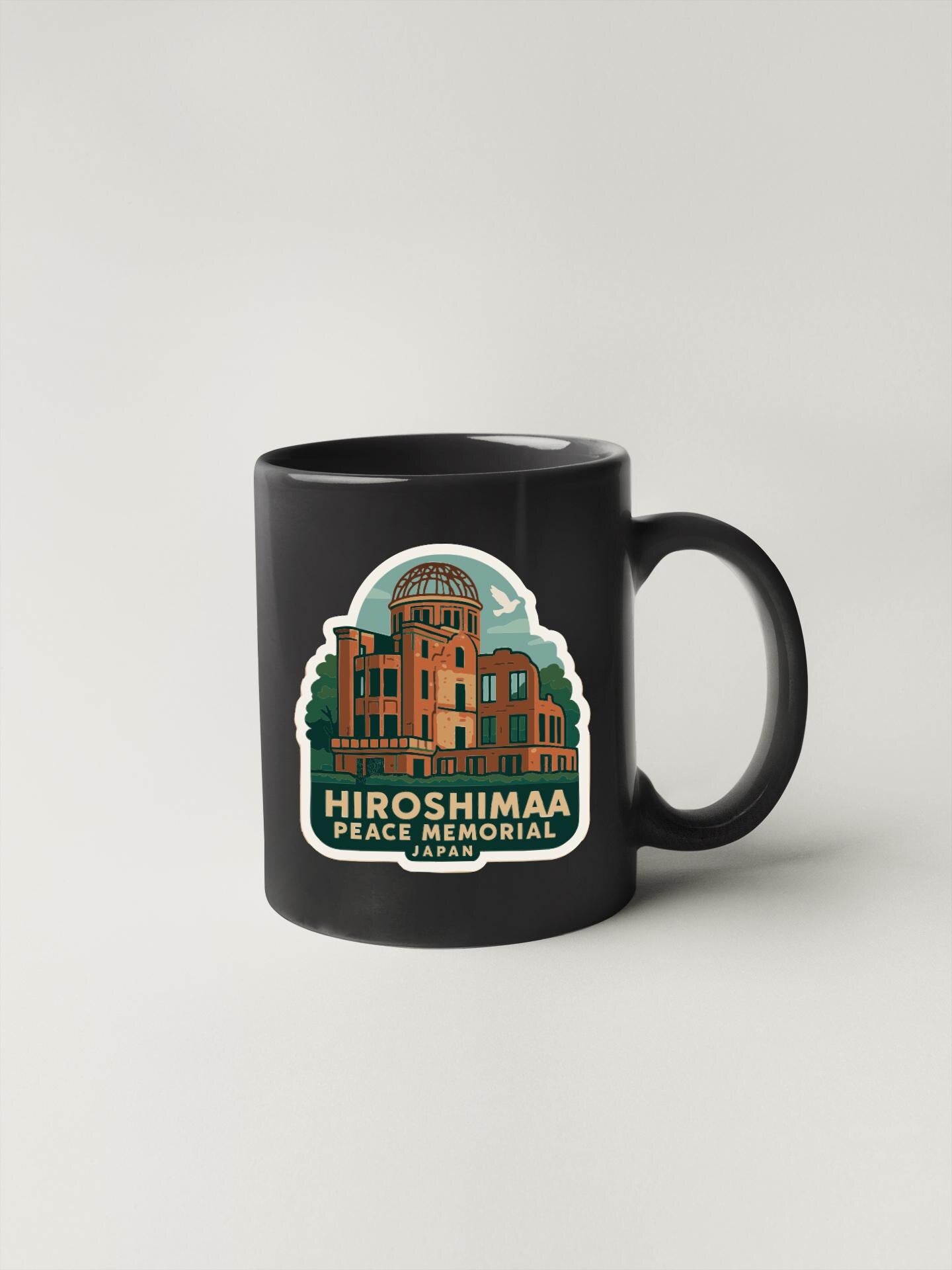A black coffee mug with a sticker depicting the Hiroshima Peace Memorial in Japan.