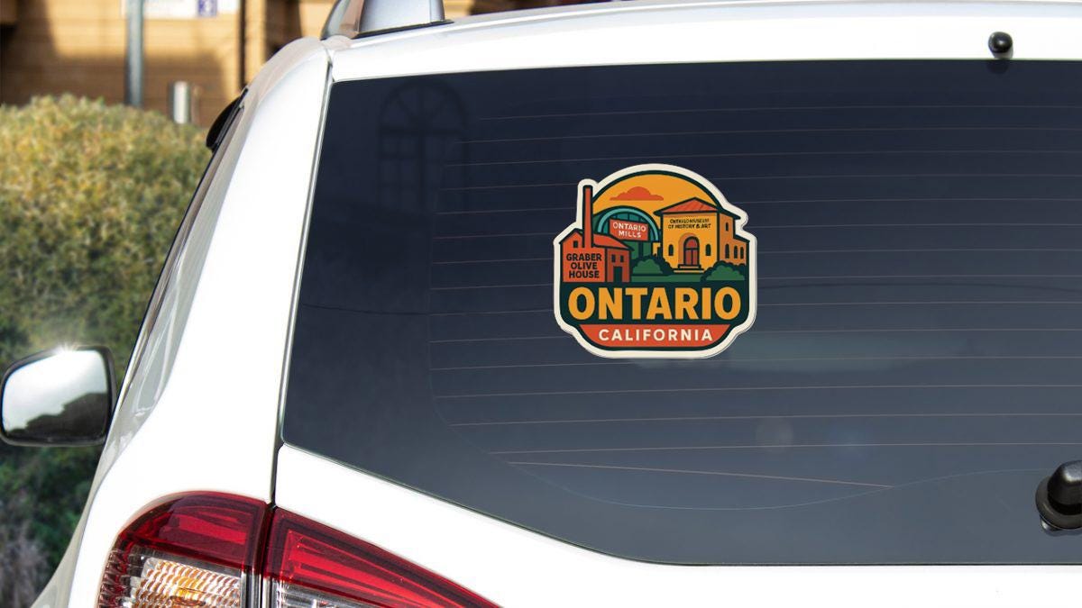 A sticker on the rear window of a white vehicle, depicting a scenic view of Ontario, California.