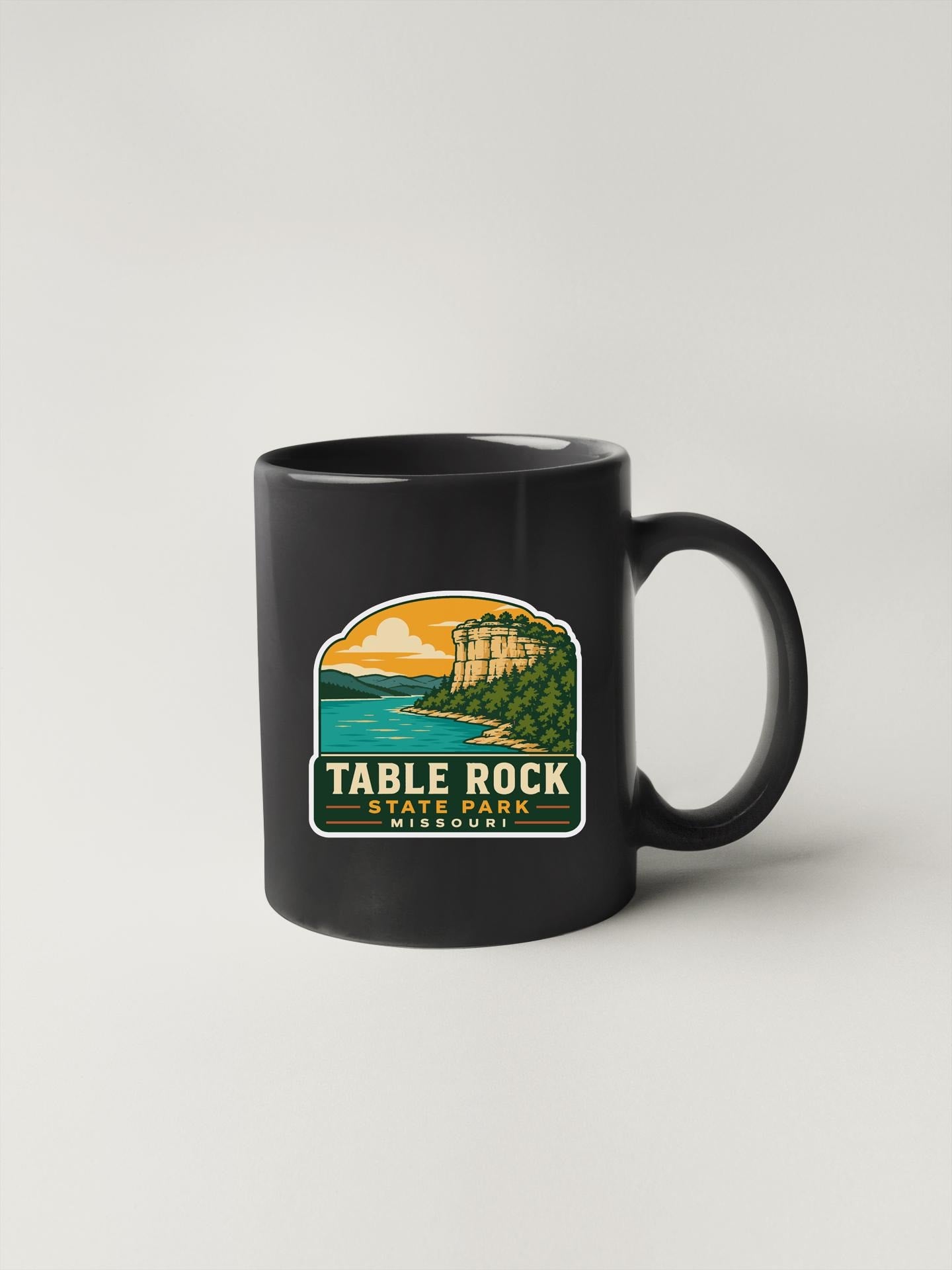 A black coffee mug with a graphic design depicting Table Rock State Park in Missouri.