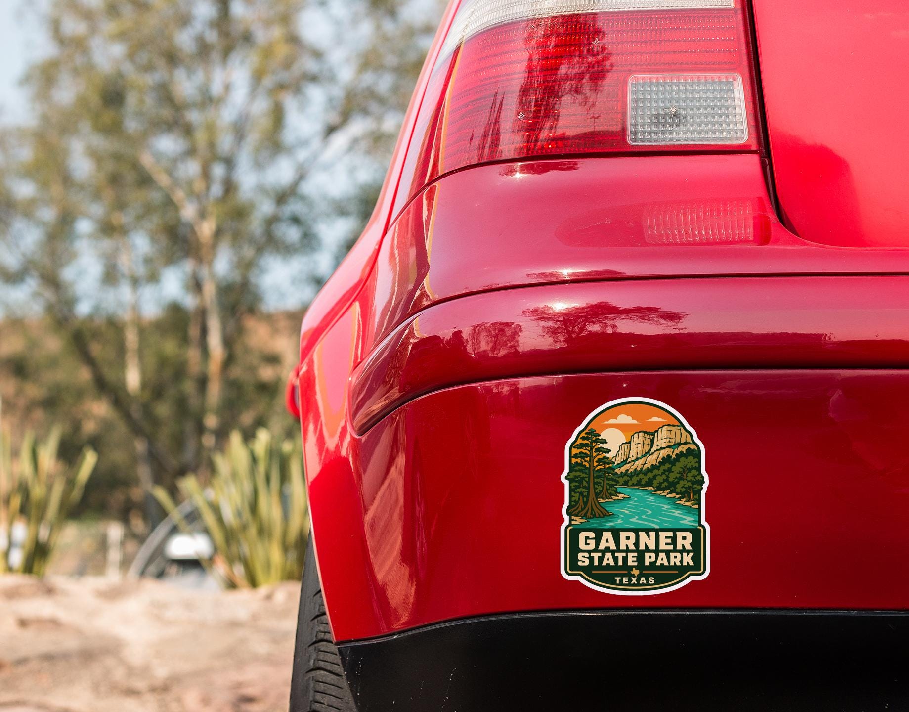 the rear end of a red car with a sticker on the trunk that says "GARNER STATE PARK TEXAS".