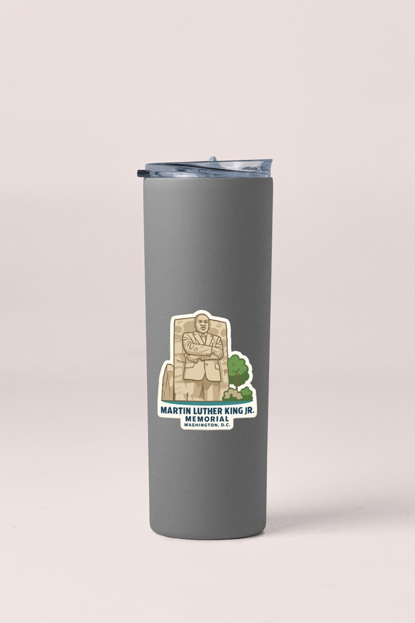 A gray tumbler with a sticker depicting Martin Luther King Jr. and the text "Martin Luther King Jr. MEMORIAL" printed on it.
