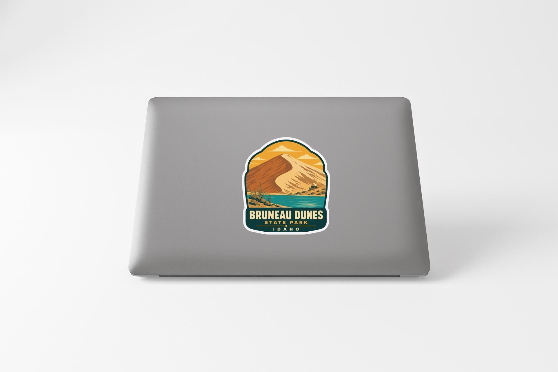 A sticker on the back of a laptop, depicting a mountain landscape with a lake and a mountain range.
