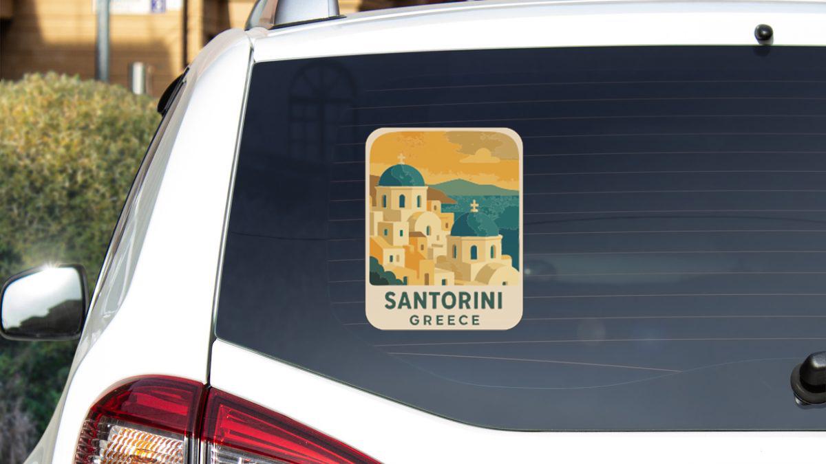 A sticker on the rear window of a car, depicting the city of Santorini, Greece.