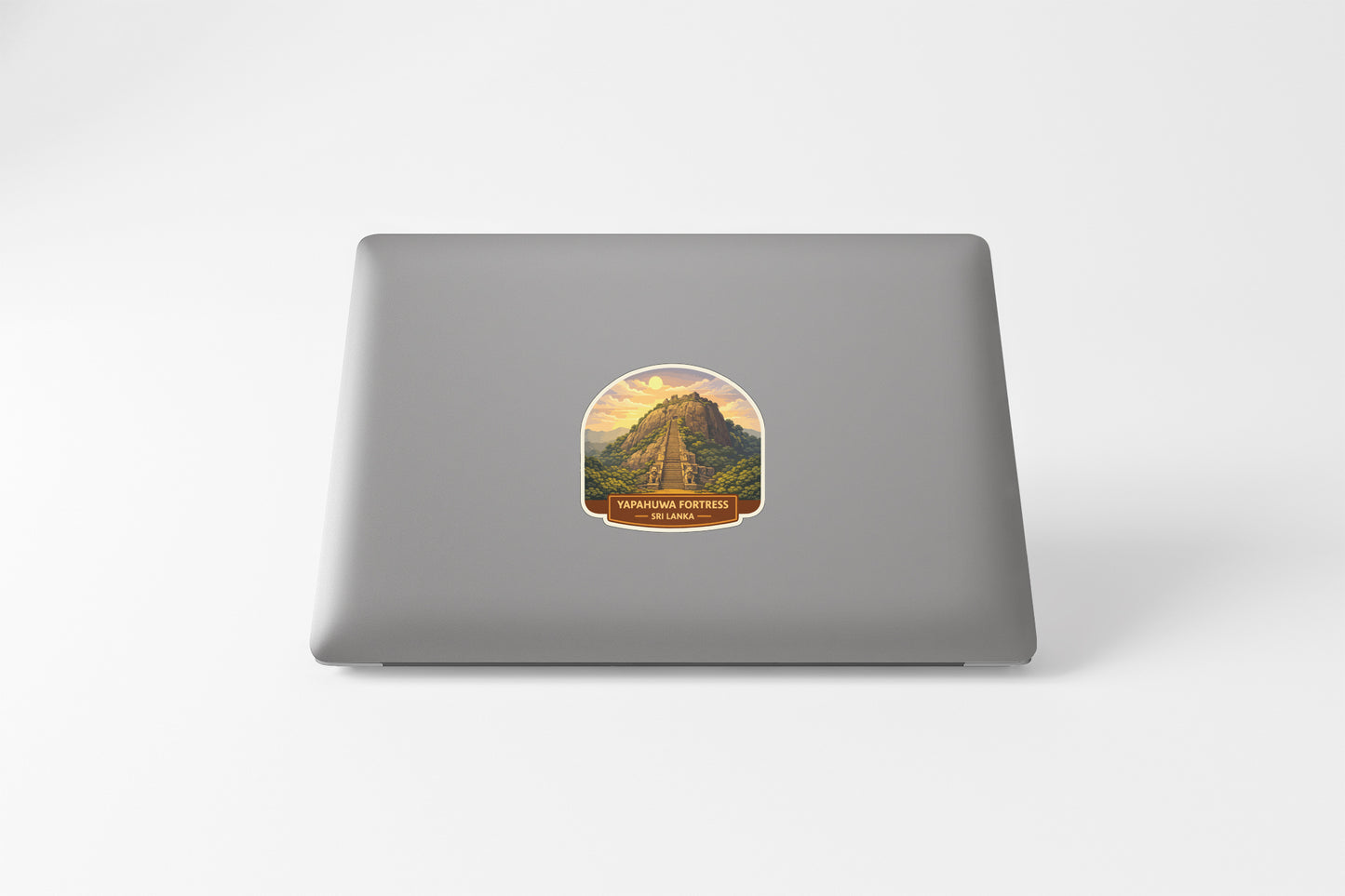 A sticker depicting a mountain landscape with a road leading up to it, placed on the back of a laptop computer.