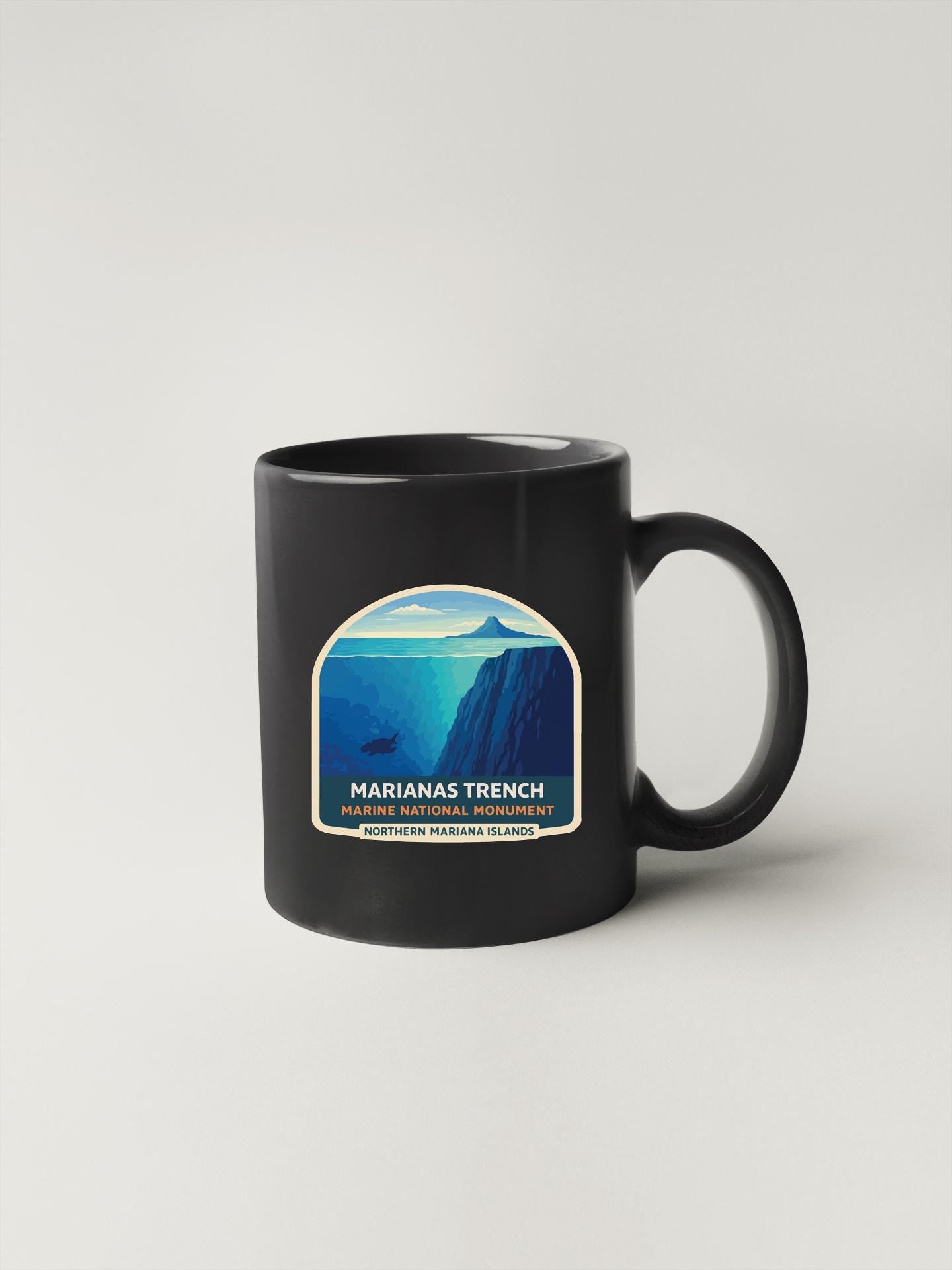 A black coffee mug with a graphic design depicting a mountainous landscape, specifically the Marianas trench, which is a UNESCO World Heritage Site.