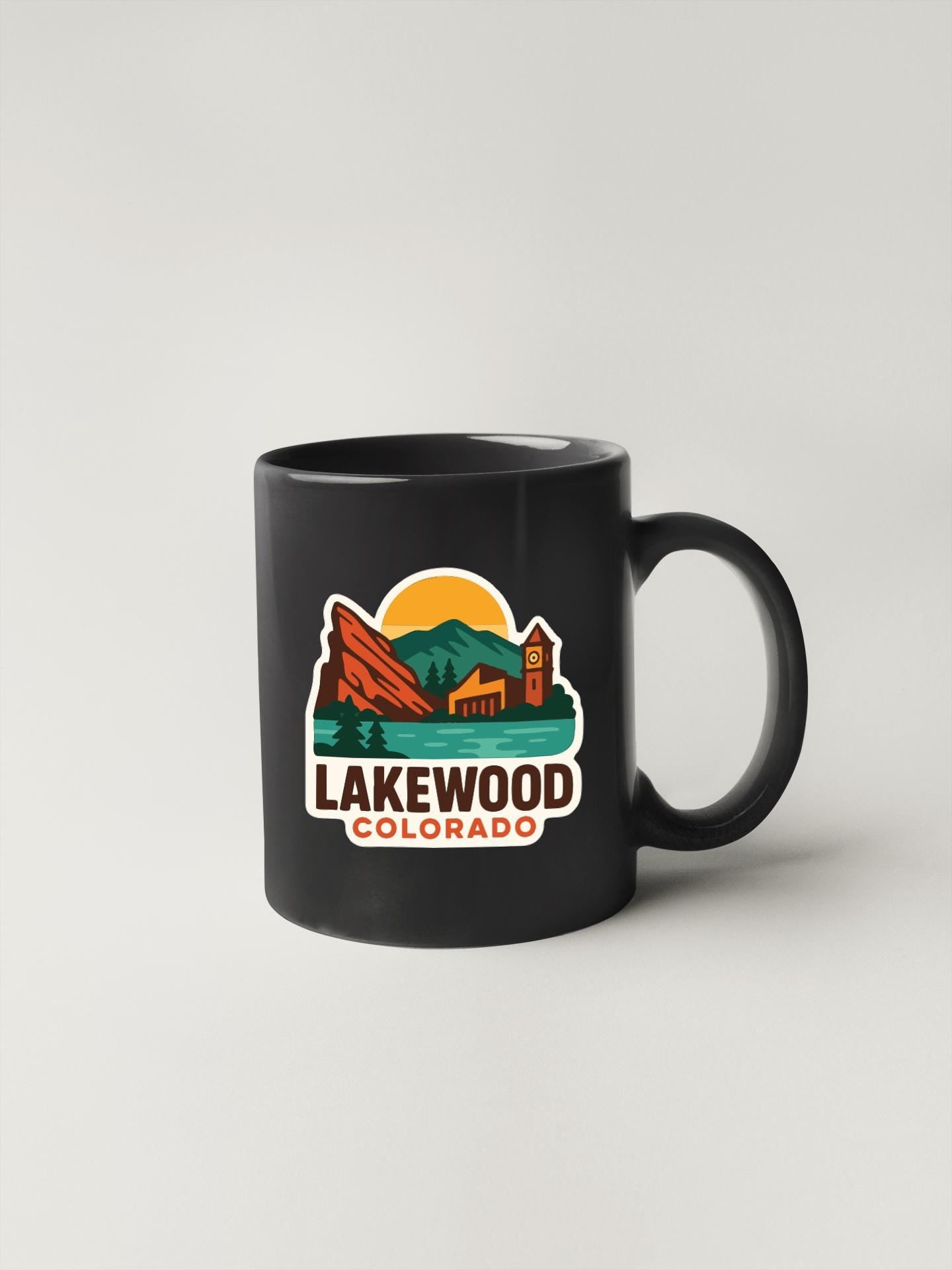 A black coffee mug with a colorful graphic design depicting Lakewood, Colorado.