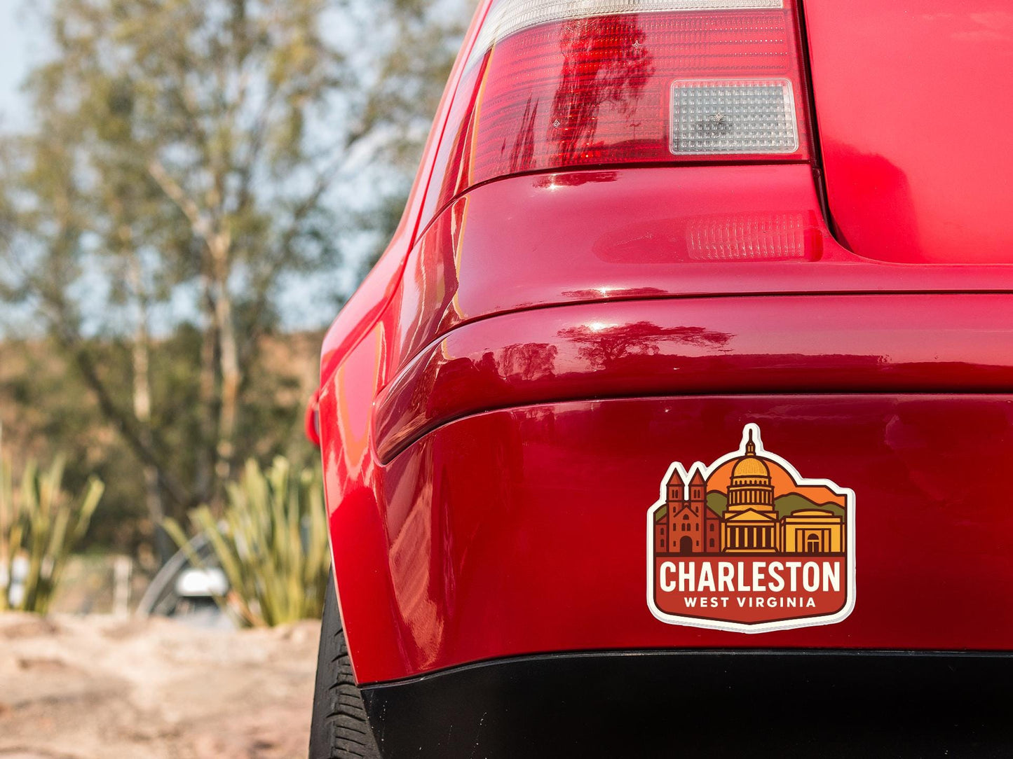 the rear end of a red car with a sticker on the trunk that says "CHARLESTON WEST VIRGINIA".