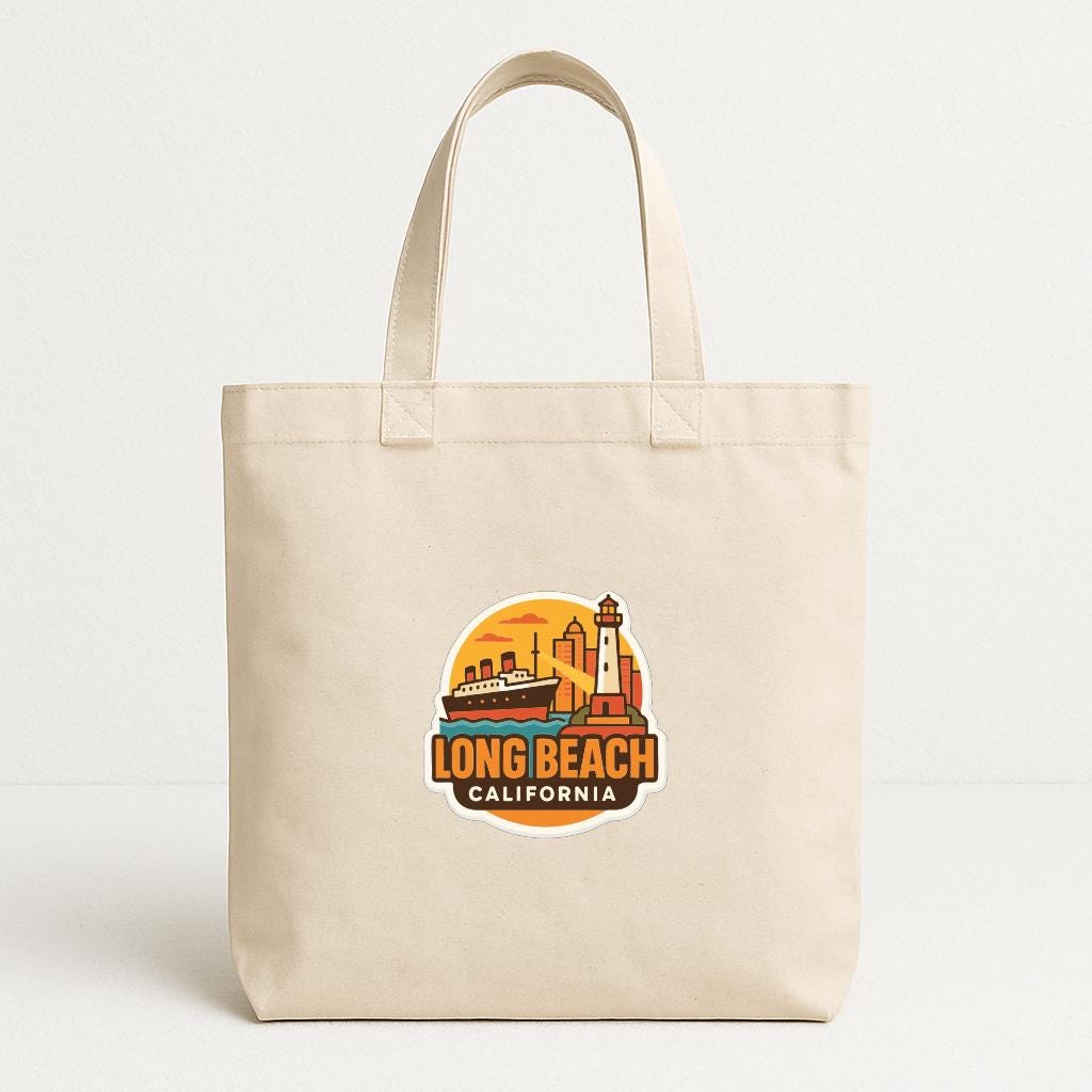 A beige tote bag with a graphic design featuring a lighthouse and a ship, along with the text "LONG BEACH CALIFORNIA".