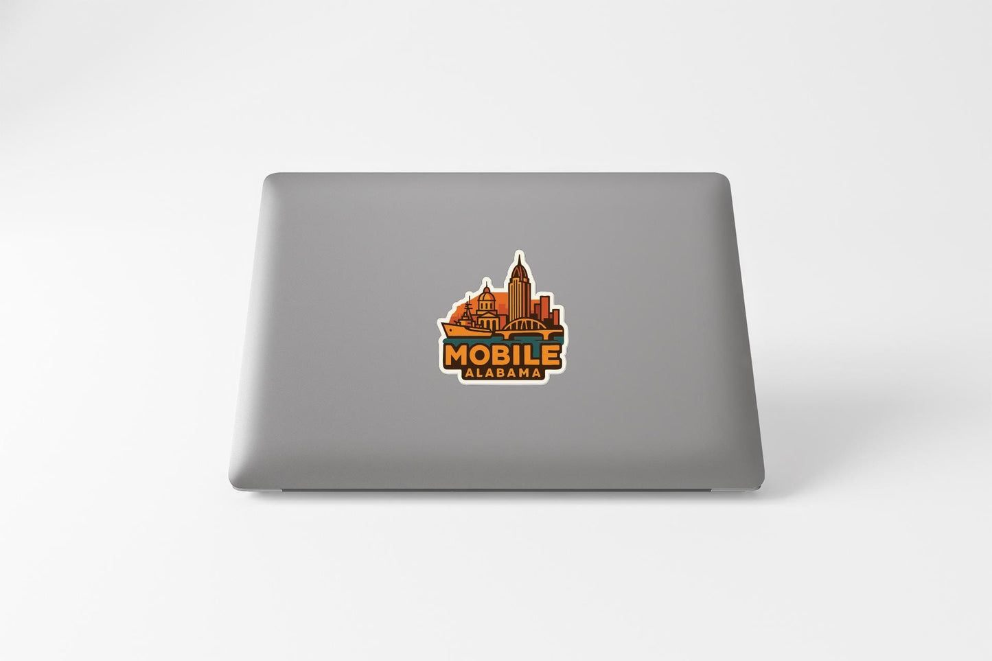 a sticker with a cityscape and the text "MOBILE ALABAMA" on the back of a laptop.