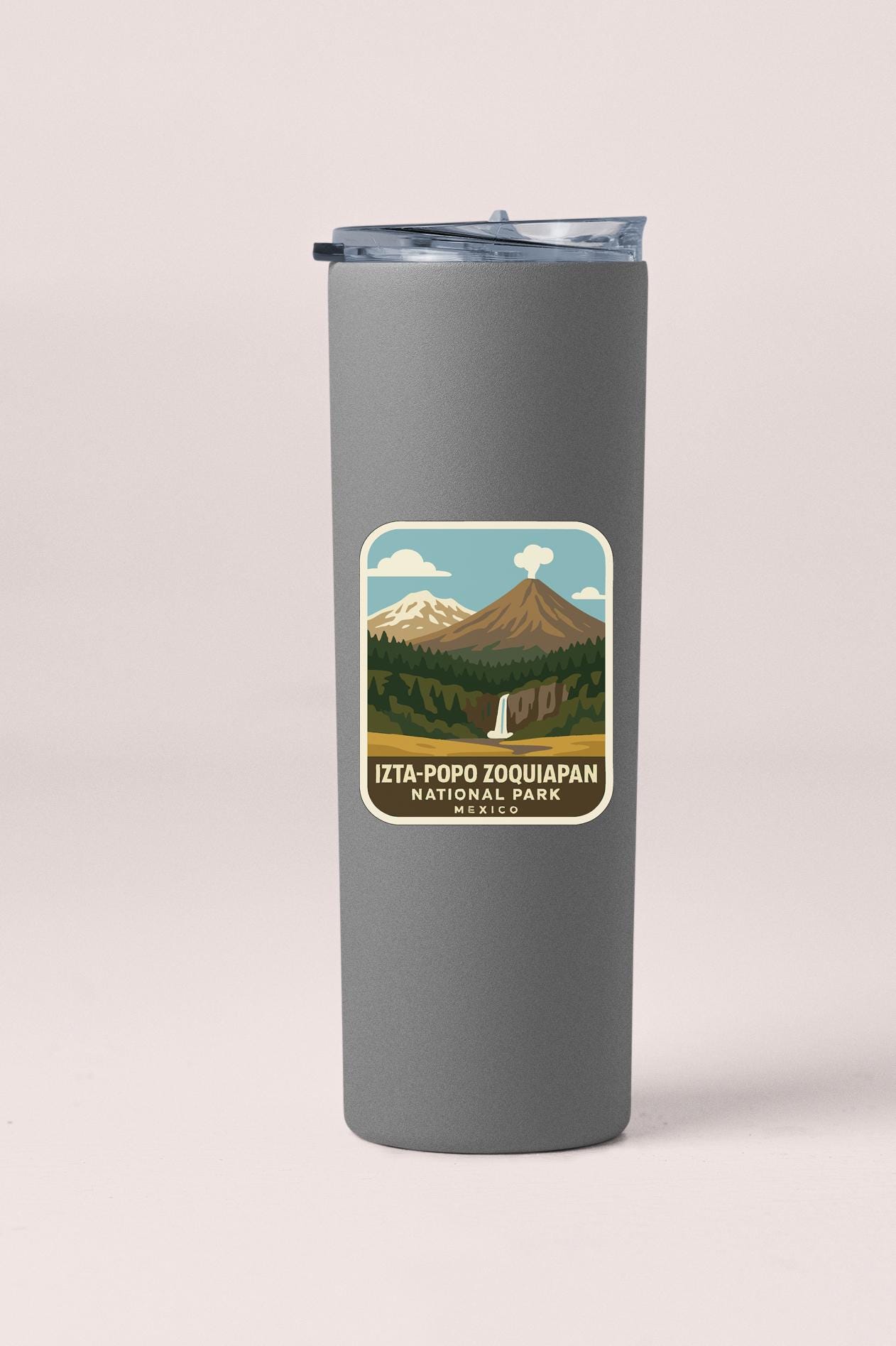 A gray insulated tumbler with a label that features a mountain landscape and a waterfall.