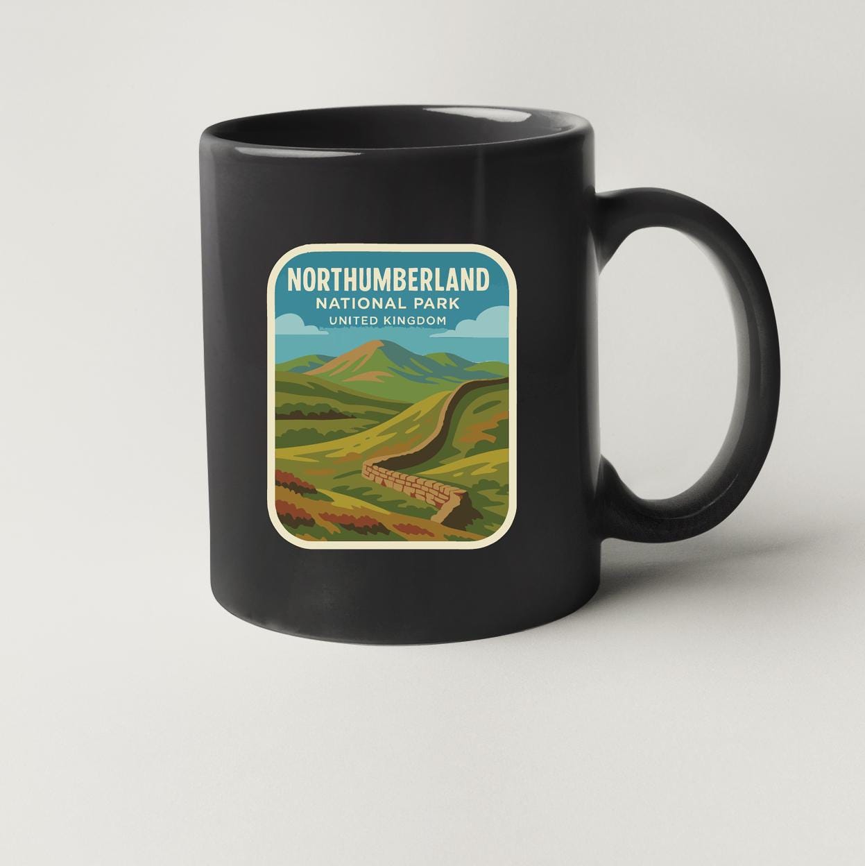 A black coffee mug with a vintage-style illustration of Northumberland National Park in the United Kingdom.