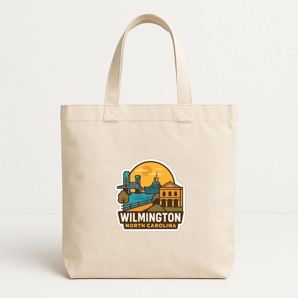 A beige tote bag with a printed design depicting a city skyline and a sunset.